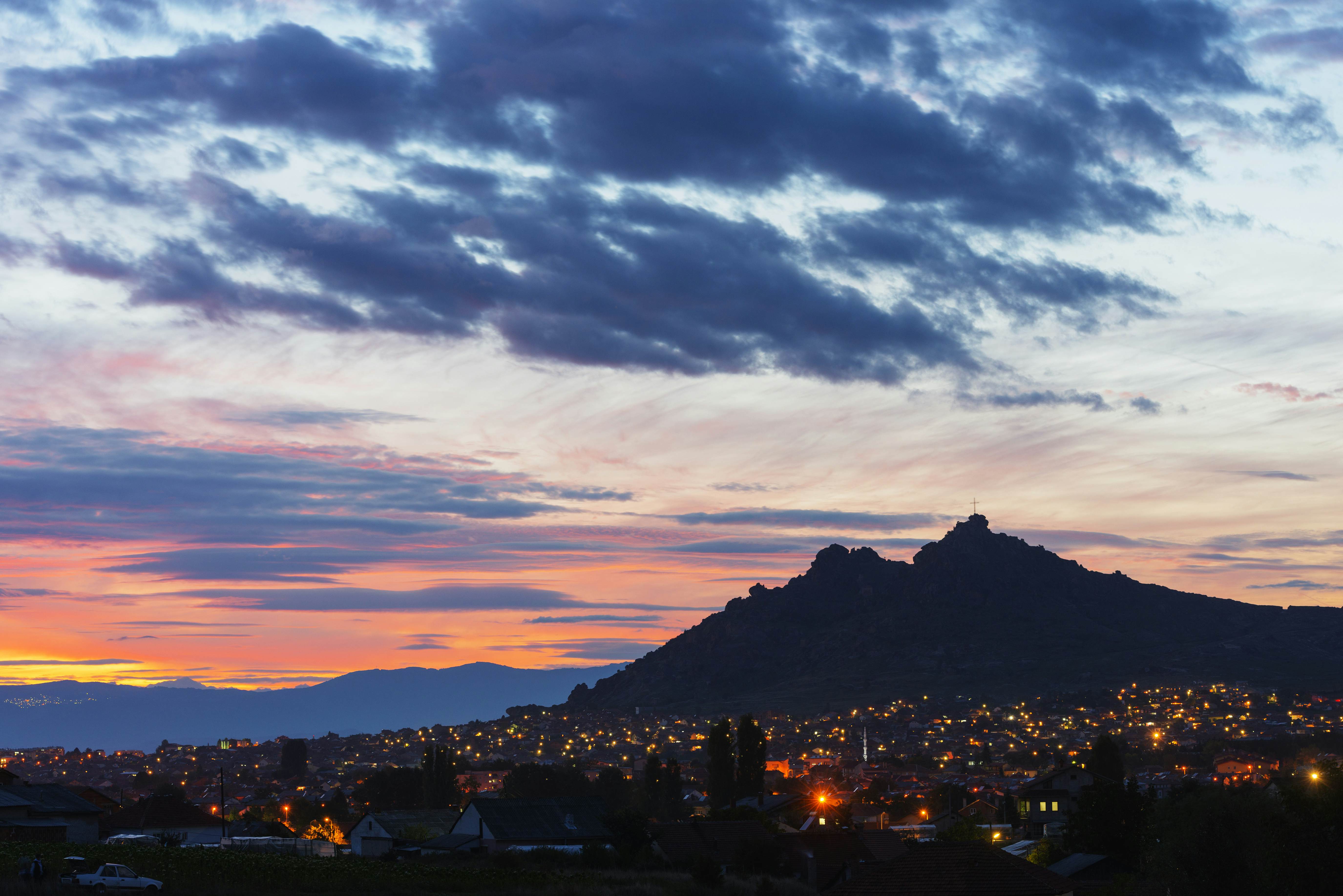 A moutain with a monastery on top silhouetted at dusk