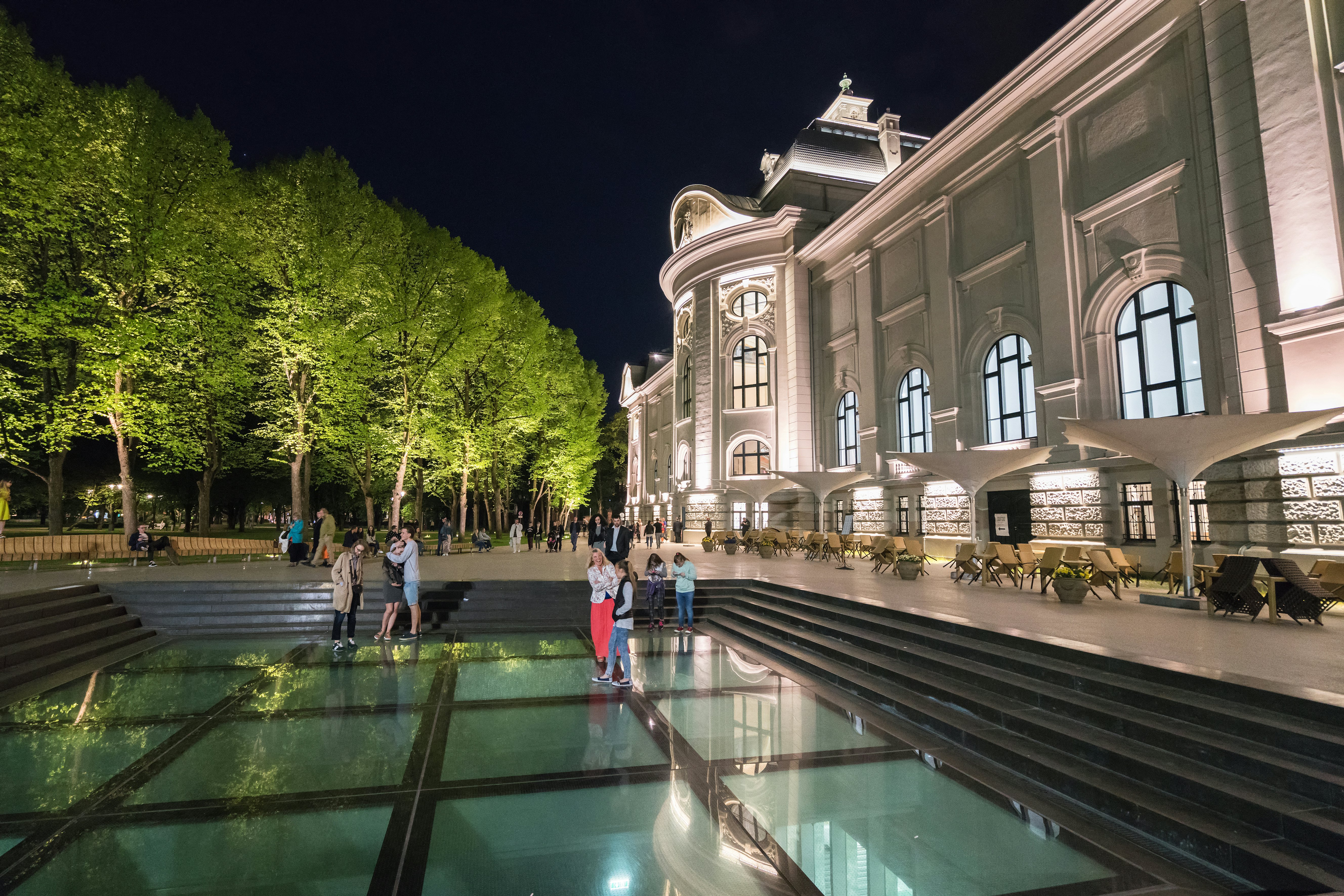 People walking next to the Latvian National Museum of Art on a summer evening in Riga.