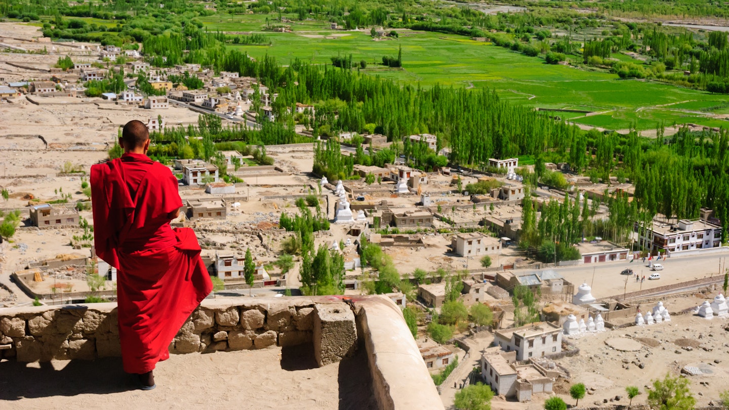A monk standing on the rooftop at Thiksey Monastery in Ladakh, India.