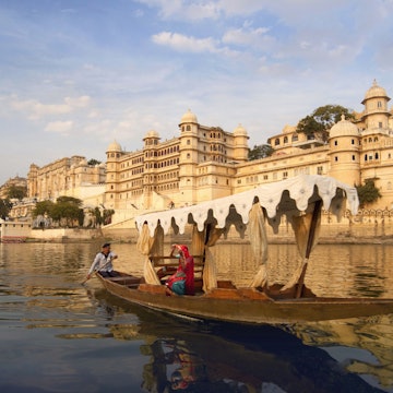 Woman on a boat on Lake Pichola beside the City Palace, Udaipur, Rajasthan, India.