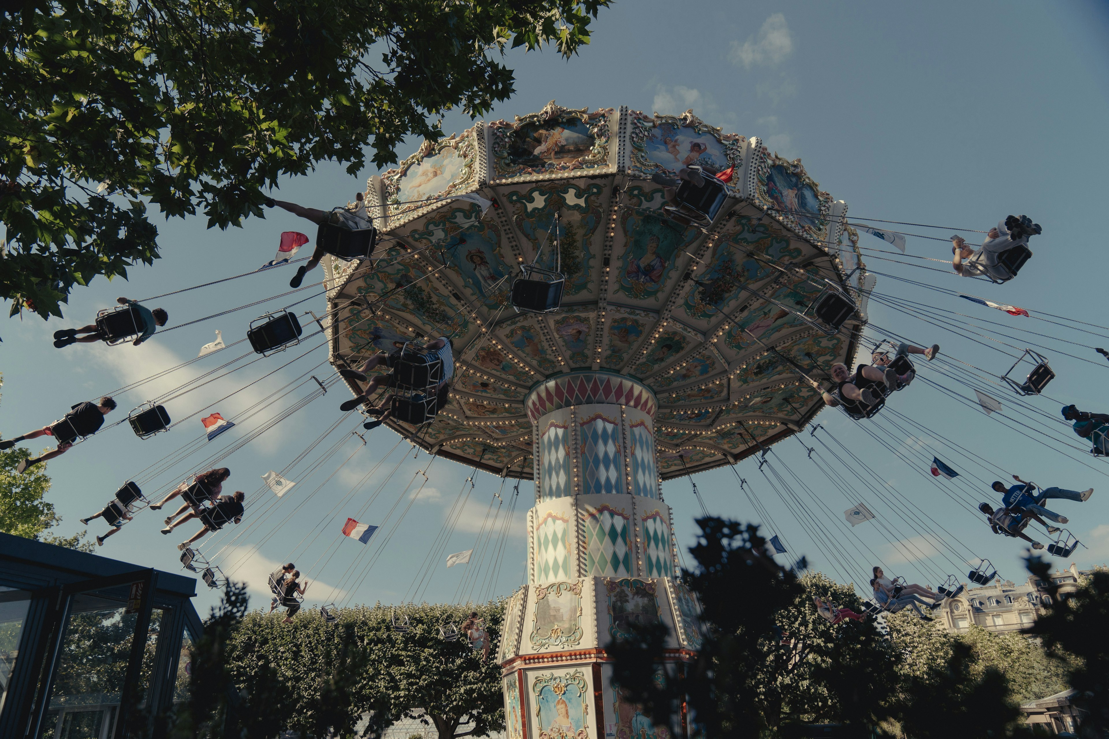 People on a swing-ride attraction at an amusement park, pictured from below.
