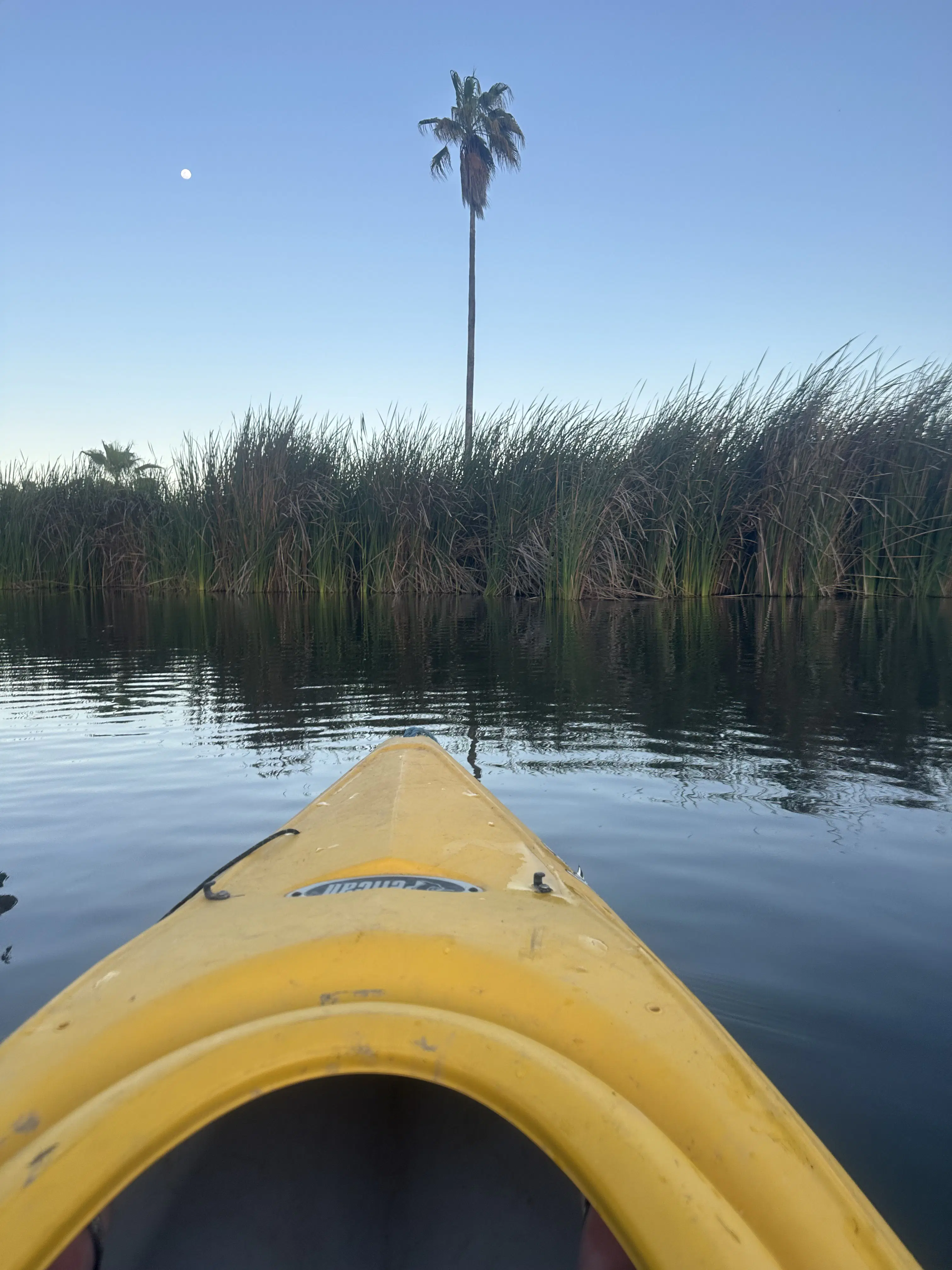 Yellow kayak on calm water at sunset.