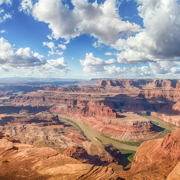 Panoramic view of young hiker standing on a cliff in scenic Dead Horse Point State Park enjoying the view on a beautiful sunny day with blue sky and dramatic clouds in summer, Utah, USA, License Type: media, Download Time: 2025-03-31T19:11:44.000Z, User: Ppeterson948, Editorial: false, purchase_order: 65050 - Digital Destinations and Articles, job: Global Publishing WIP, client: Global Publishing WIP, other: Pia Peterson Haggarty // SS Comp Ingestion