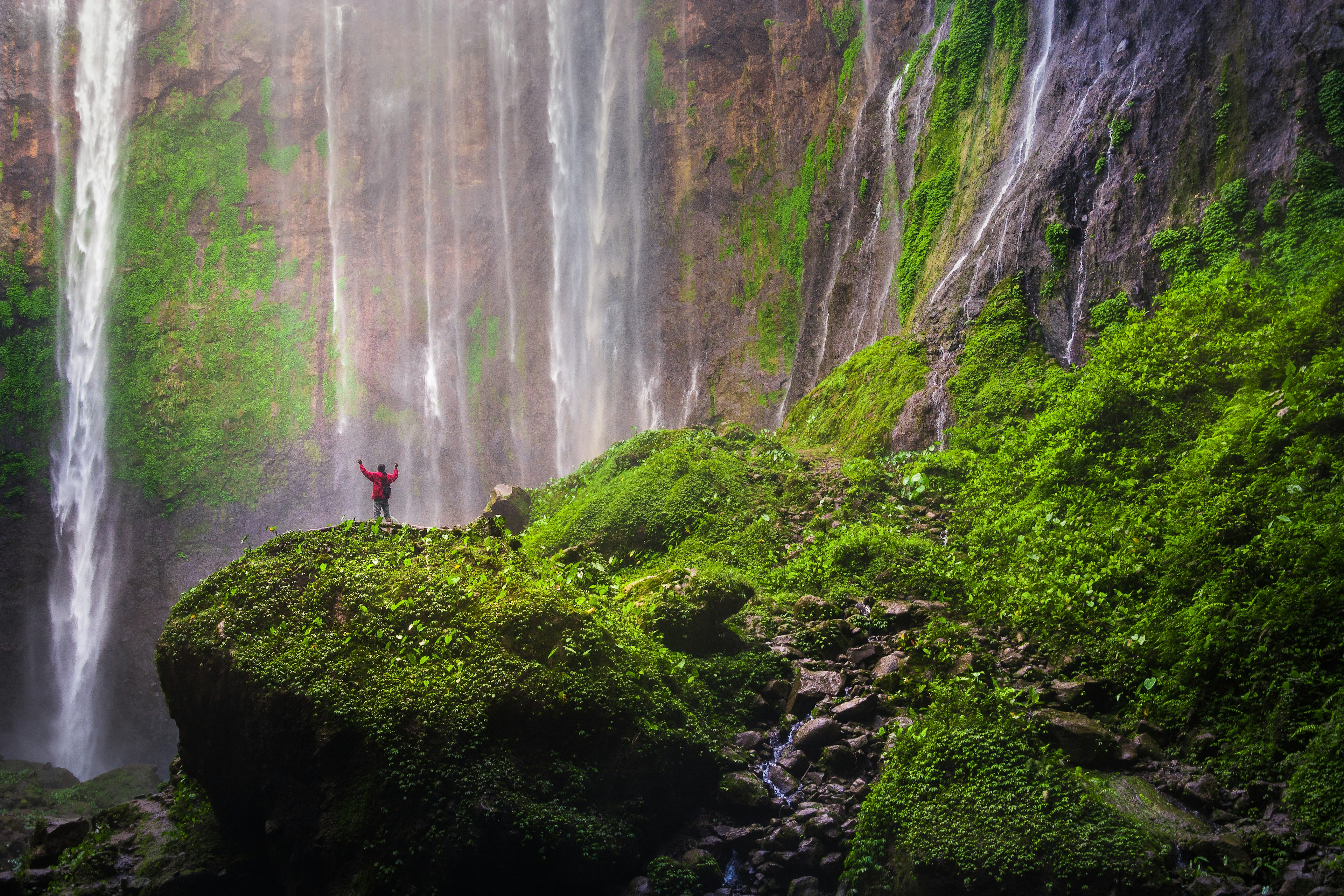 A man standing on the rocks at Tumpak Sewu waterfall, East Java, Indonesia.