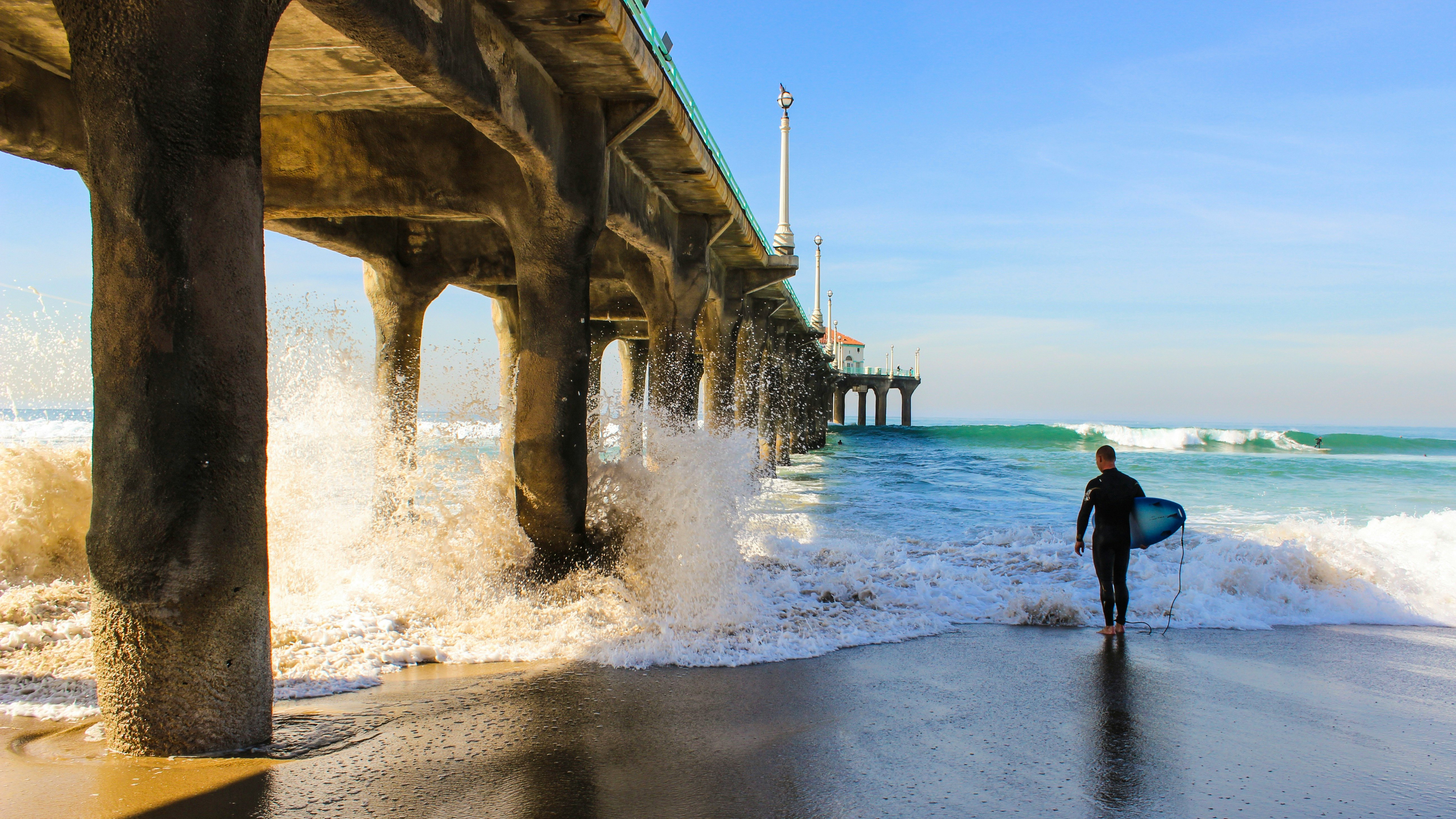 A surfer and his borad under Manhattan beach pier at Los Angeles California.