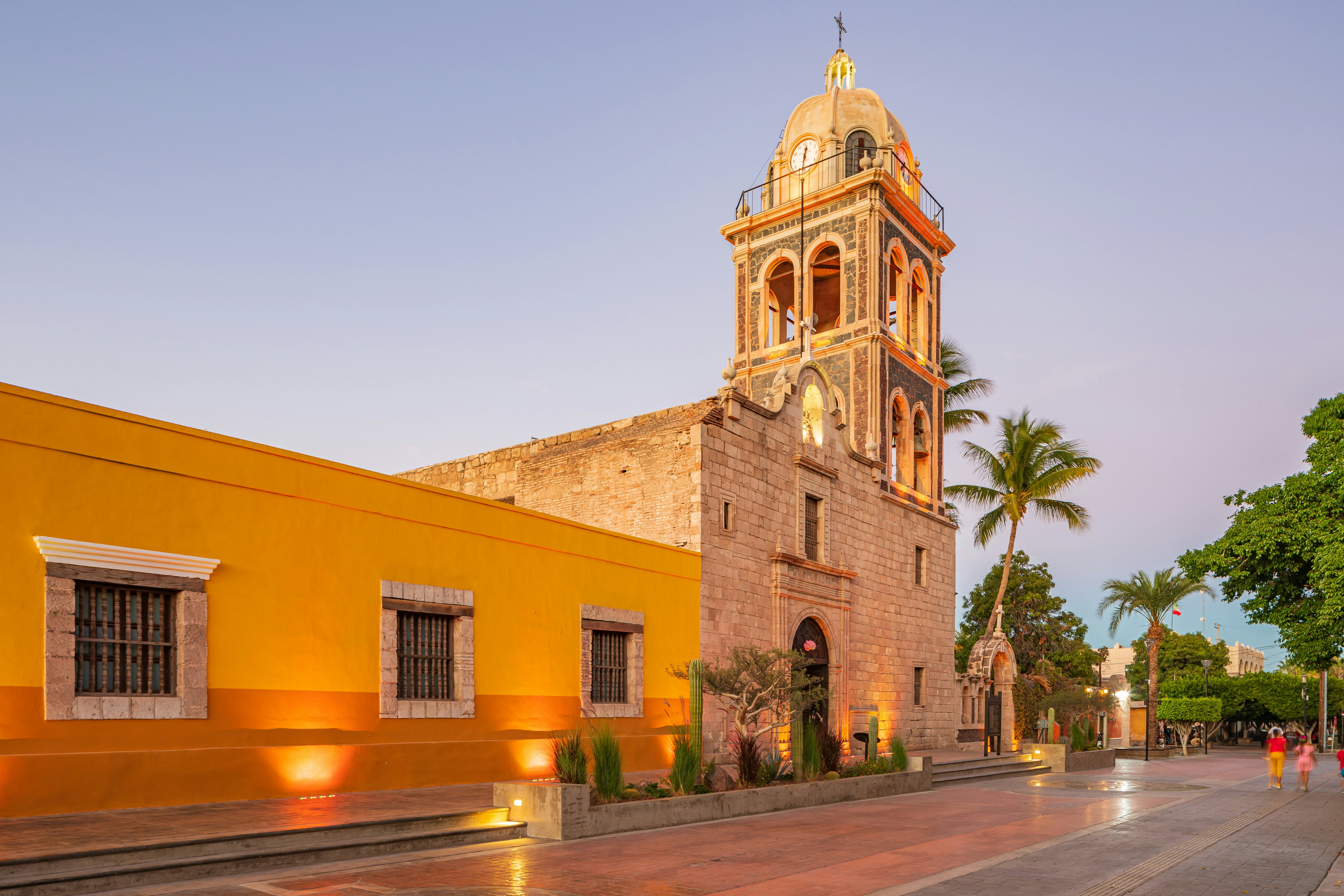 A yellow-walled church with a dome at the top of its bell tower.