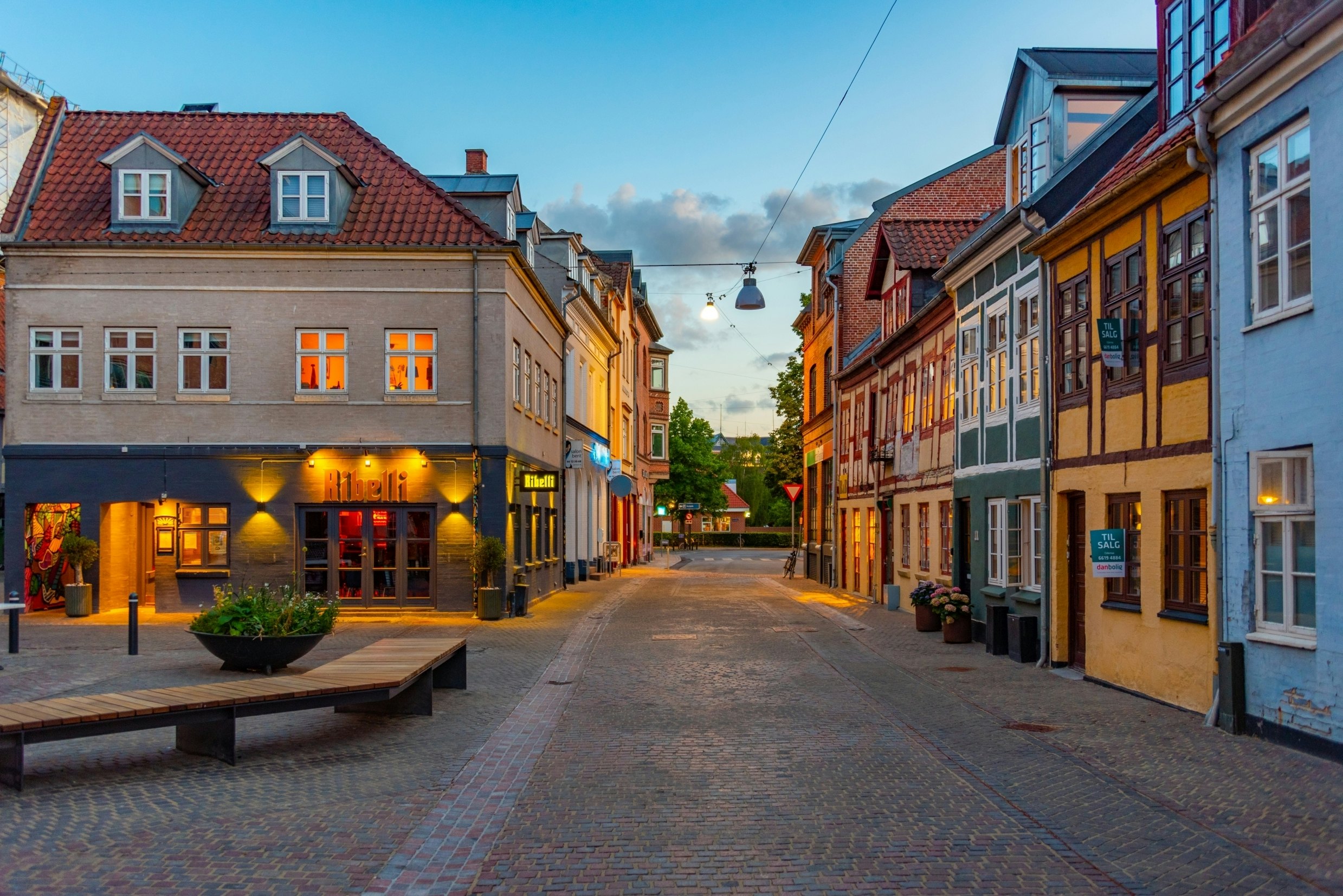 Night view of a cobblestone street with lighted buildings on either side.