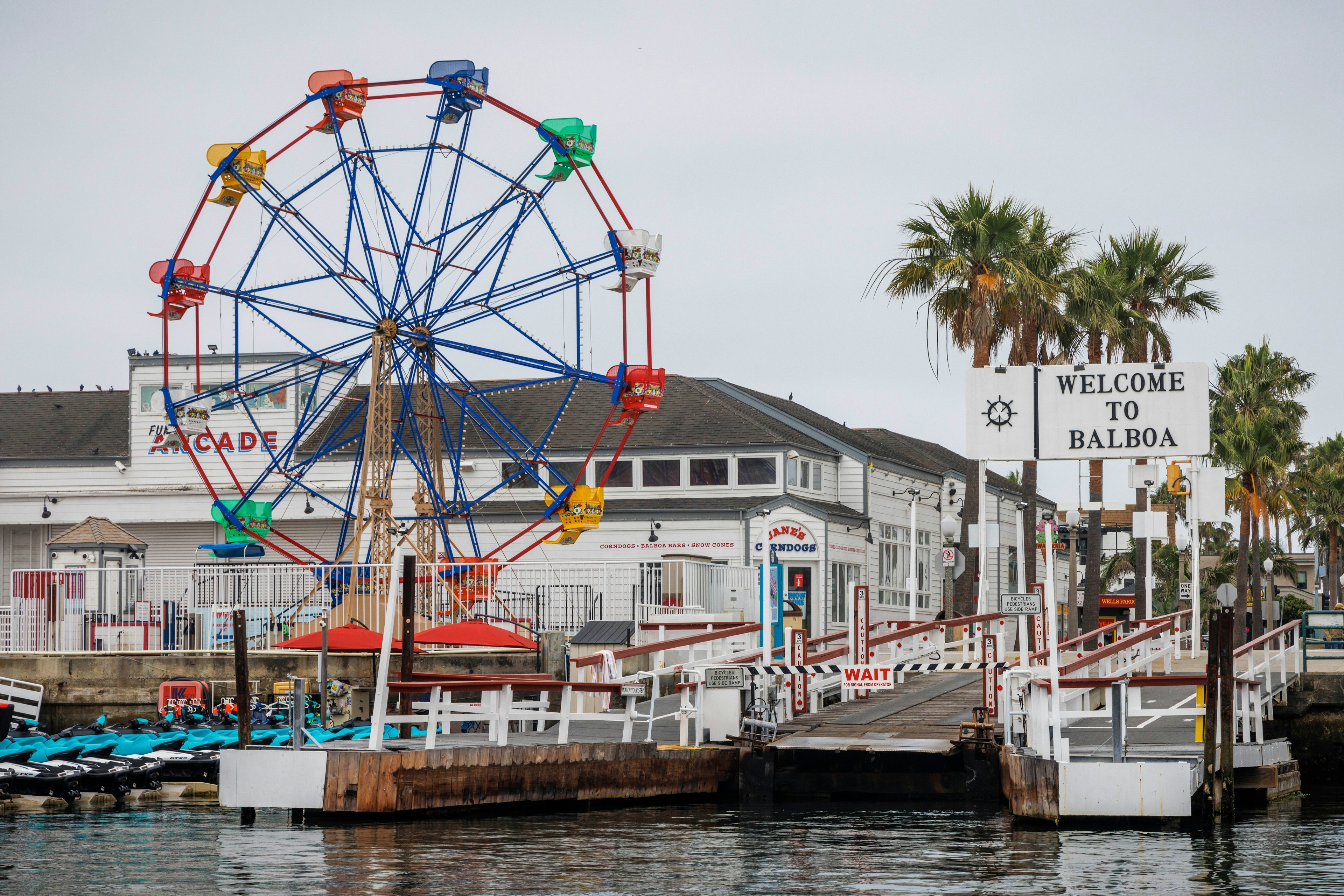 Image of ferris wheel bordering the sea with a sign reading "Welcome to Balboa" on the right.