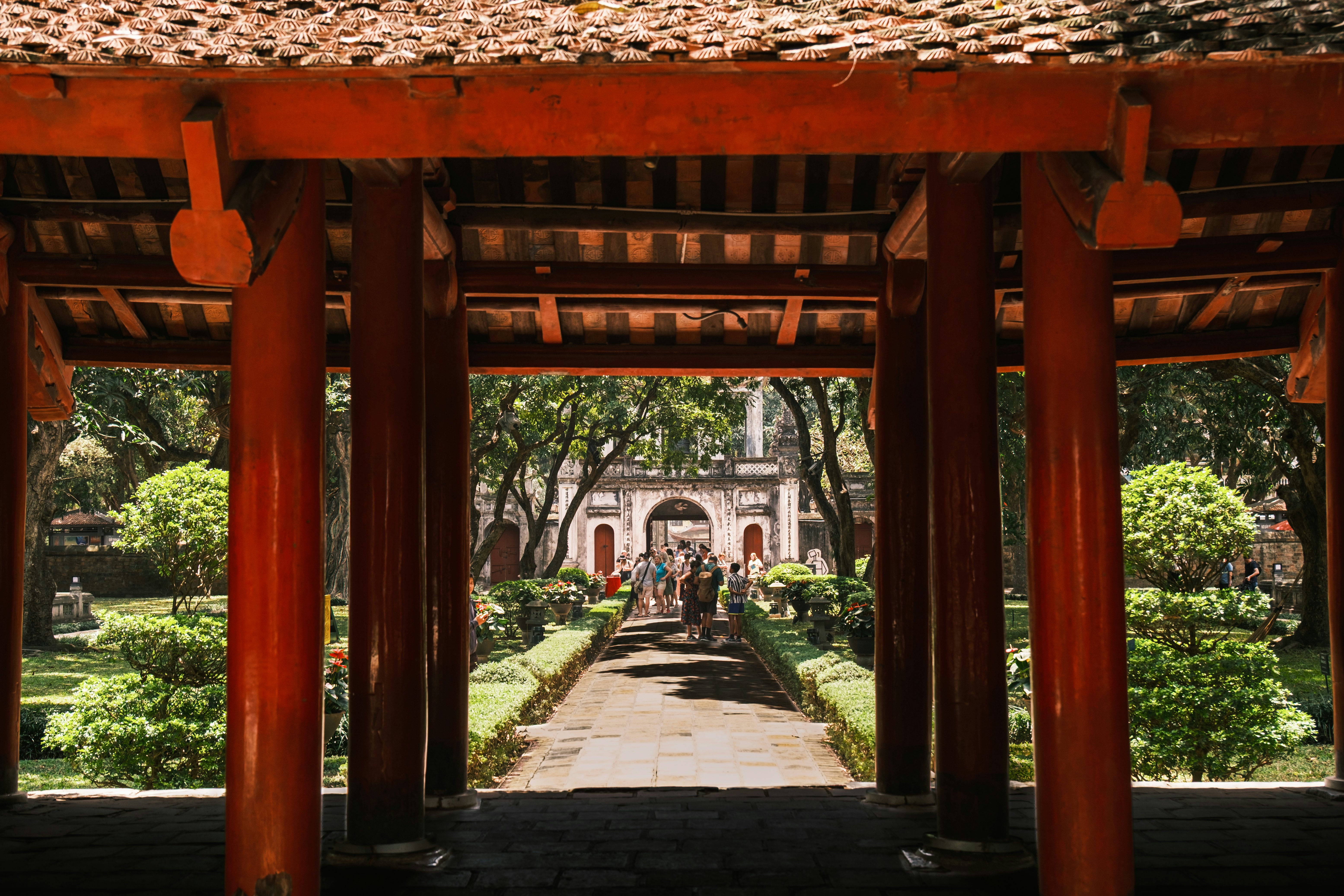 A red-pillared gazebo-like structure frames manicured gardens and a stone walkway