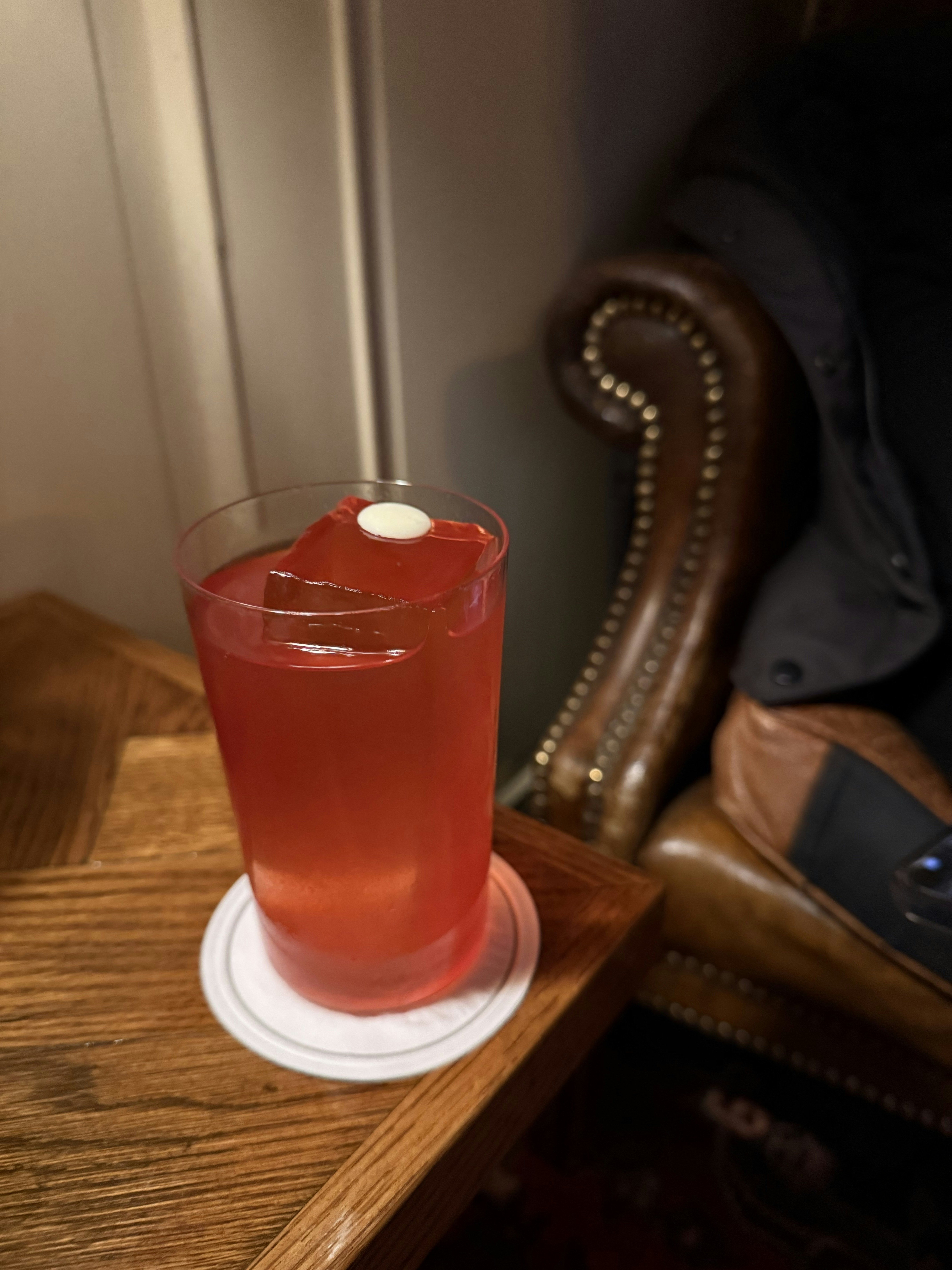 Close-up of red drink in a tall glass on a wooden table.