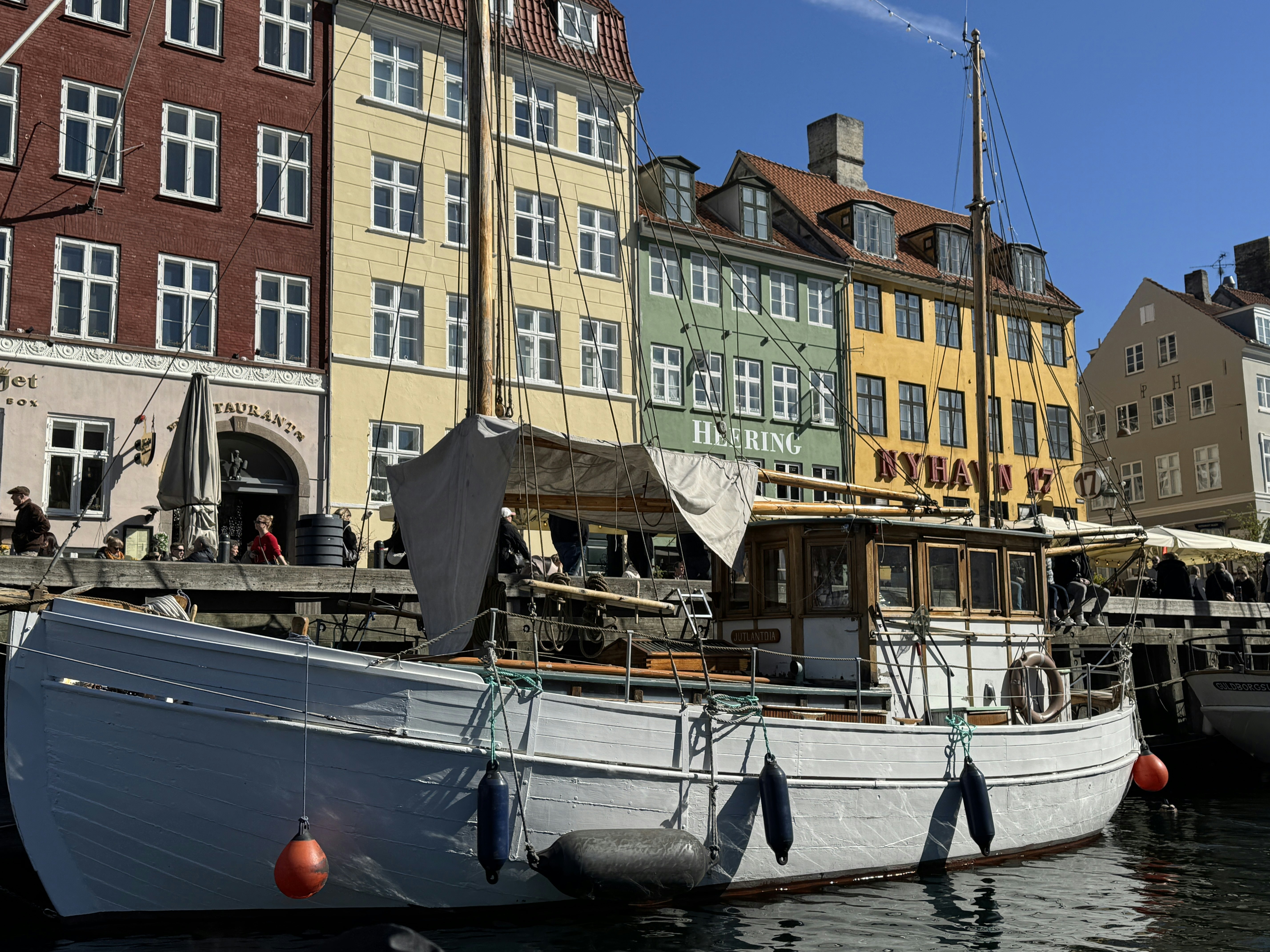 Close-up of white canal boat on the water with colorful brick buildings in the background in Nyhavn, Copenhagen.