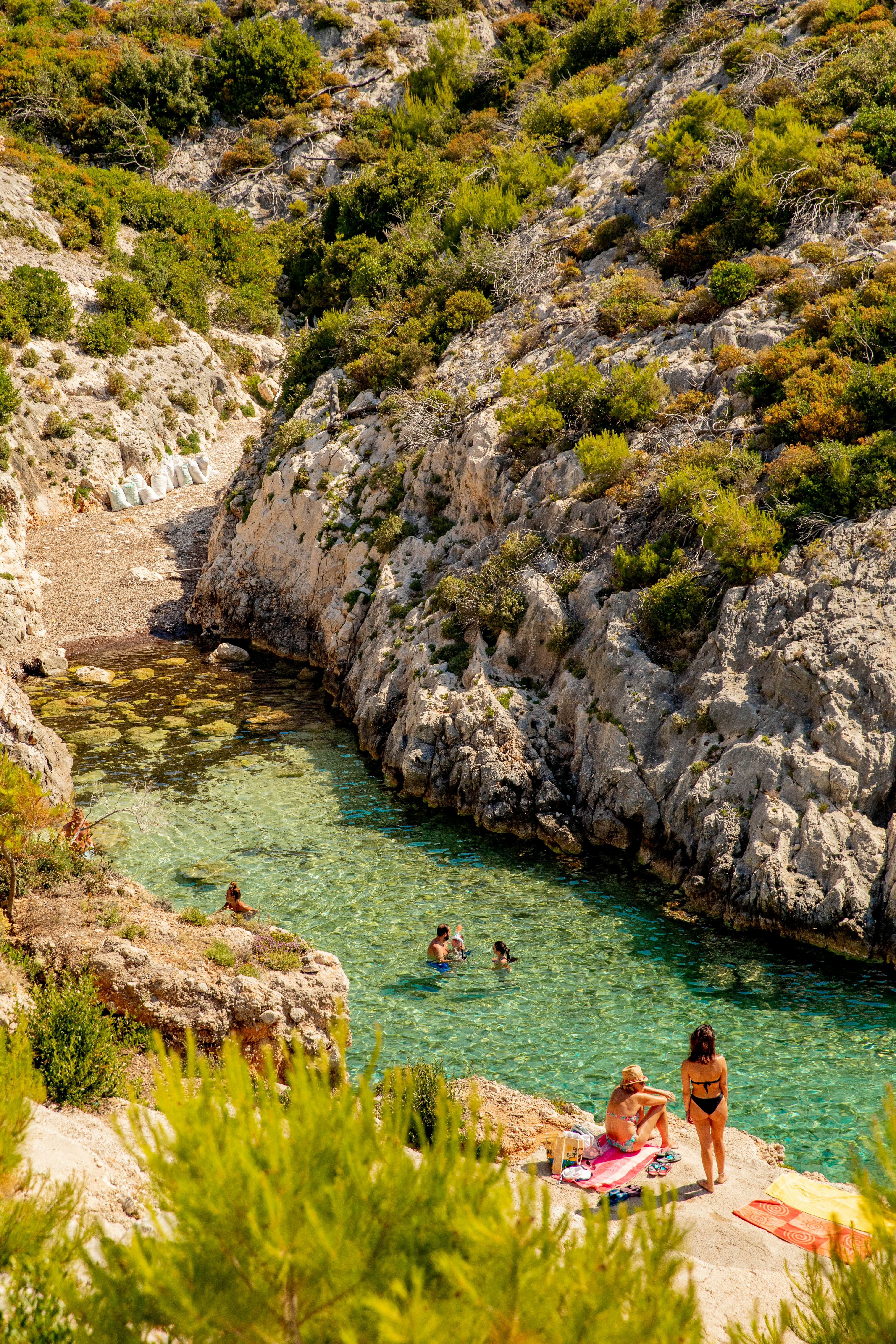 People swimming in the clear, almost green waters of a bay in Zakynthos.