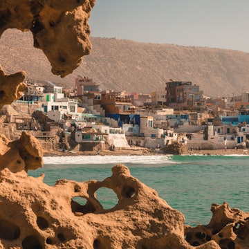 IMSOUANE, MOROCCO - CIRCA DECEMBER 2019: View of a Moroccan fishing village with the rocky terrain and ocean in the foreground, and a cliff in the background, License Type: media, Download Time: 2024-09-02T14:46:17.000Z, User: jennifermcdonagh63, Editorial: true, purchase_order: 56500, job: Trade & Ref, client: Where to go when with kids, other: Jen McDonagh