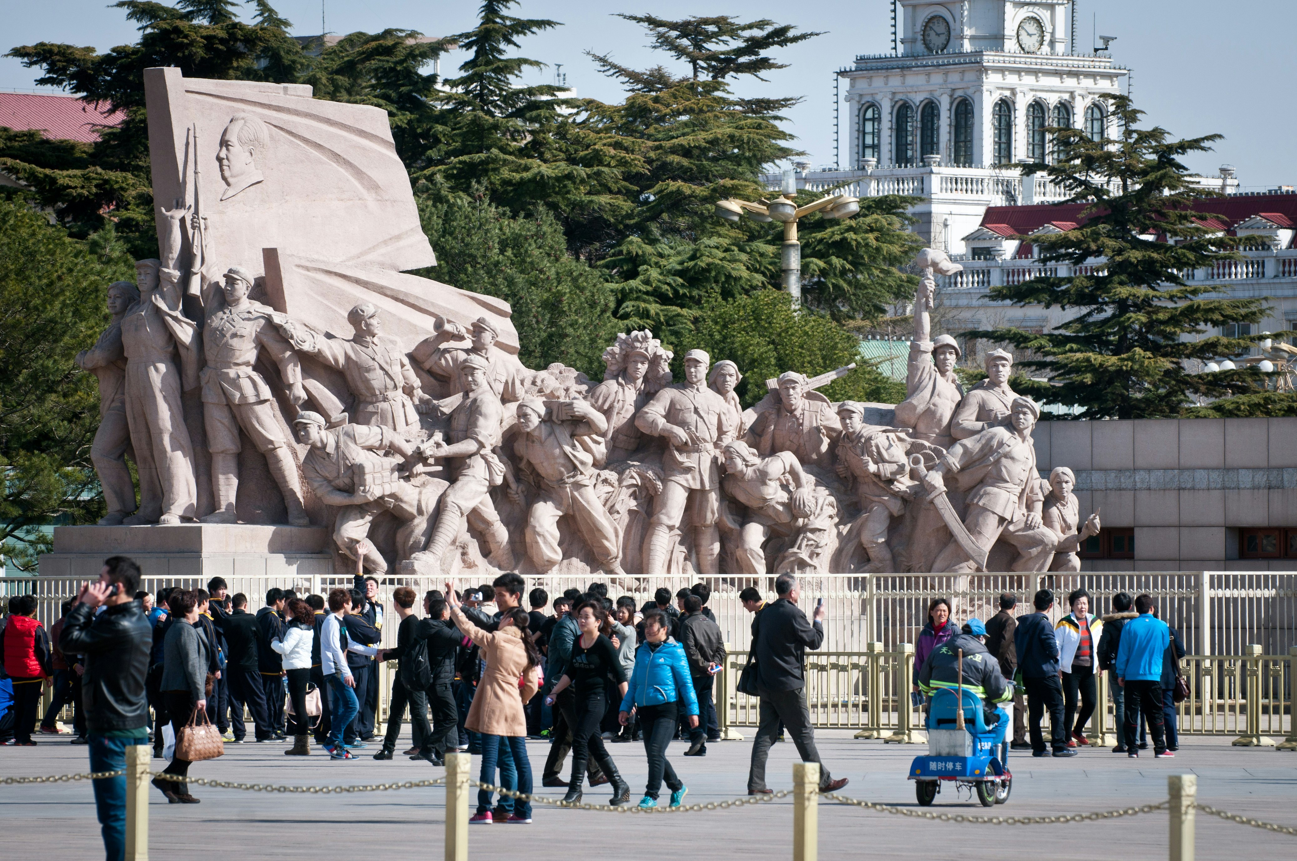 Visitors in front of a revolutionary statue next to the Chairman Mao Memorial Hall in Tiananmen Square, Beijing, China.