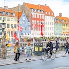 Copenhagen, Denmark - May 23 2022: Cyclist, pedestrians and tourists in Christianshavn, Nyhavn neighborhood, Copenhagen, Denmark with traditional Danish colorful houses, boats and flags on background, License Type: media, Download Time: 2025-02-07T14:32:44.000Z, User: meg3348277, Editorial: true, purchase_order: 56530 - Guidebooks, job: Global Publishing-WIP, client: Denmark & the Faroe Islands 10, other: Megan Cassidy