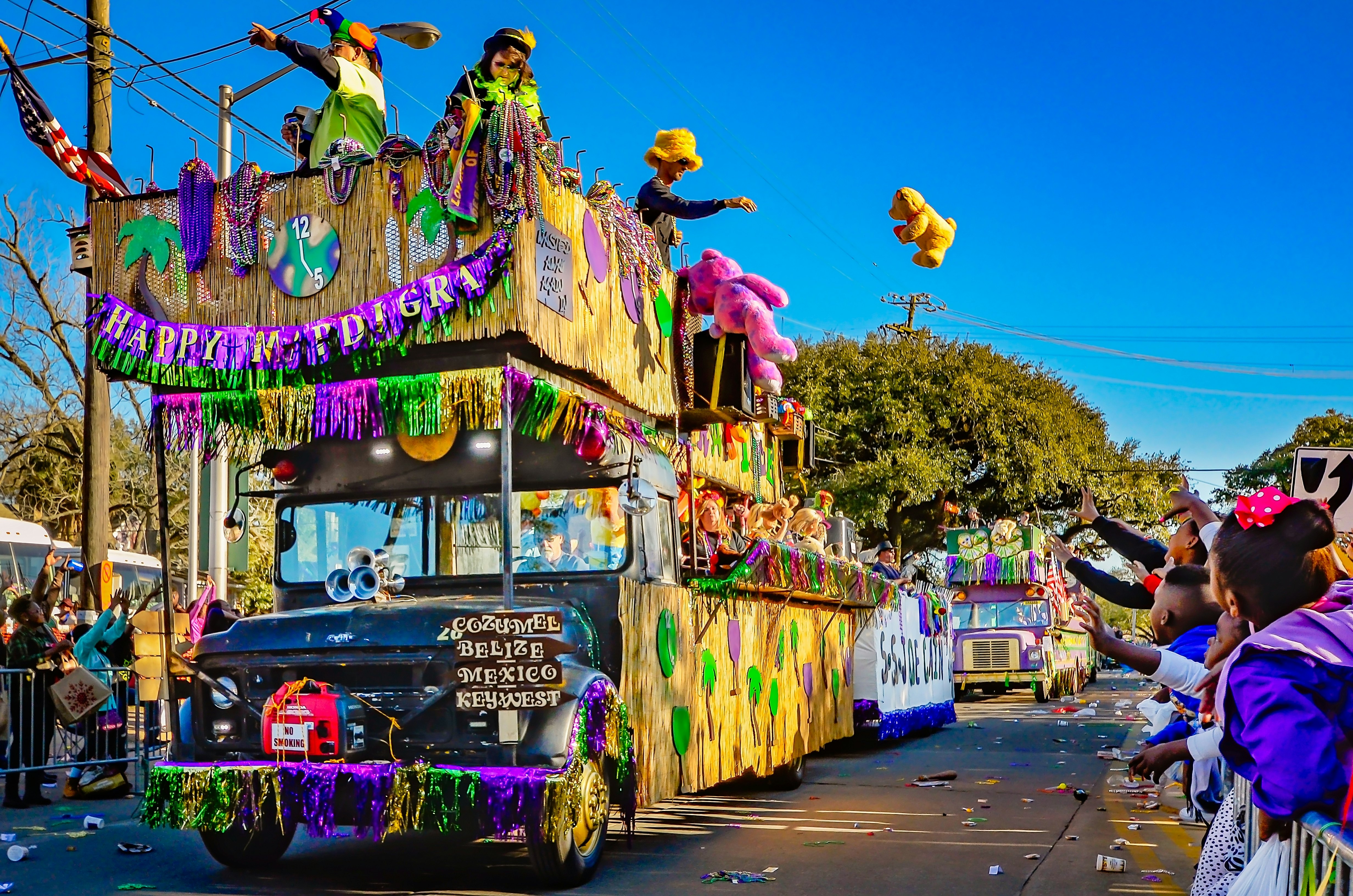 Mardi Gras floats make their way down a city street as onlookers cheer them on.