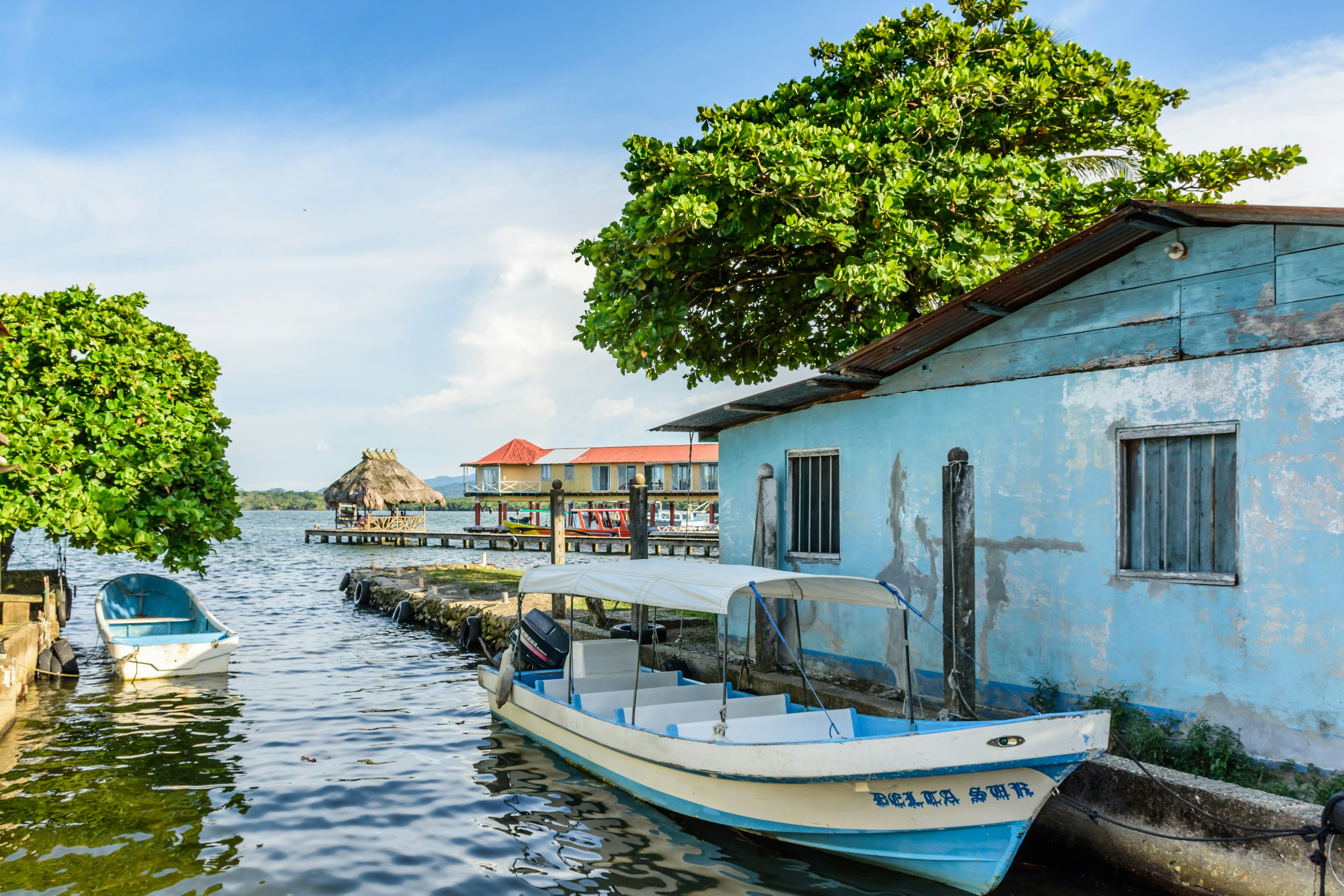 A small motorboat moored near a rowboat on the edge of a lake.