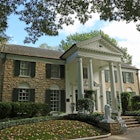 Graceland.
architecture, attraction, blue, branches, building, clouds, driveway, elvis, famous, garden, home, house, landmark, leaves, memphis, nature, outdoors, pillars, presley, sky, tennessee, tour, tourism, travel, trees, white, windows