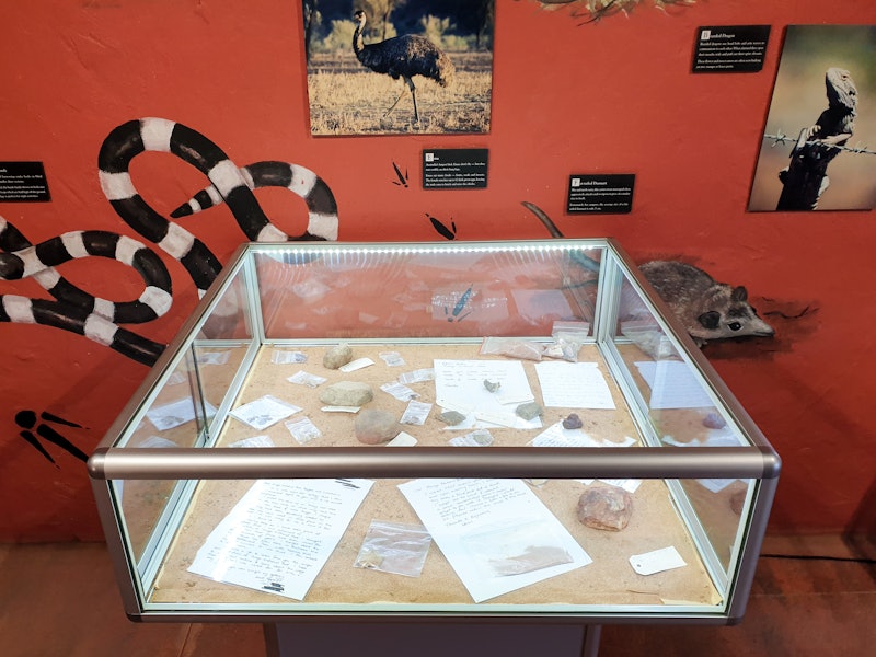 A glass case filled with rocks, hand written letters and various tags