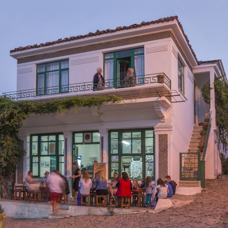 People gather outside a busy bar at dusk.