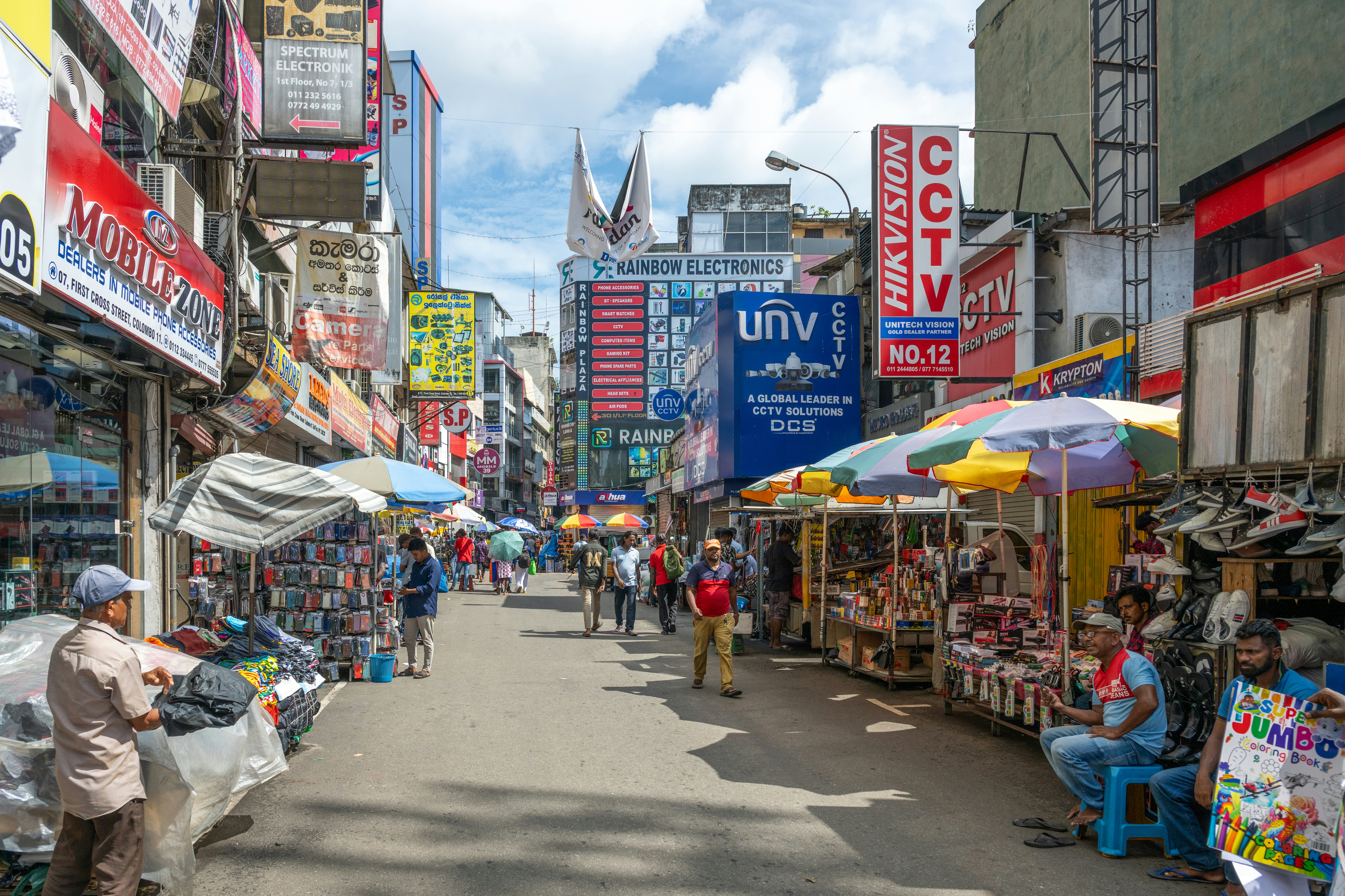 A busy street lined with eletronics stores and market stalls.