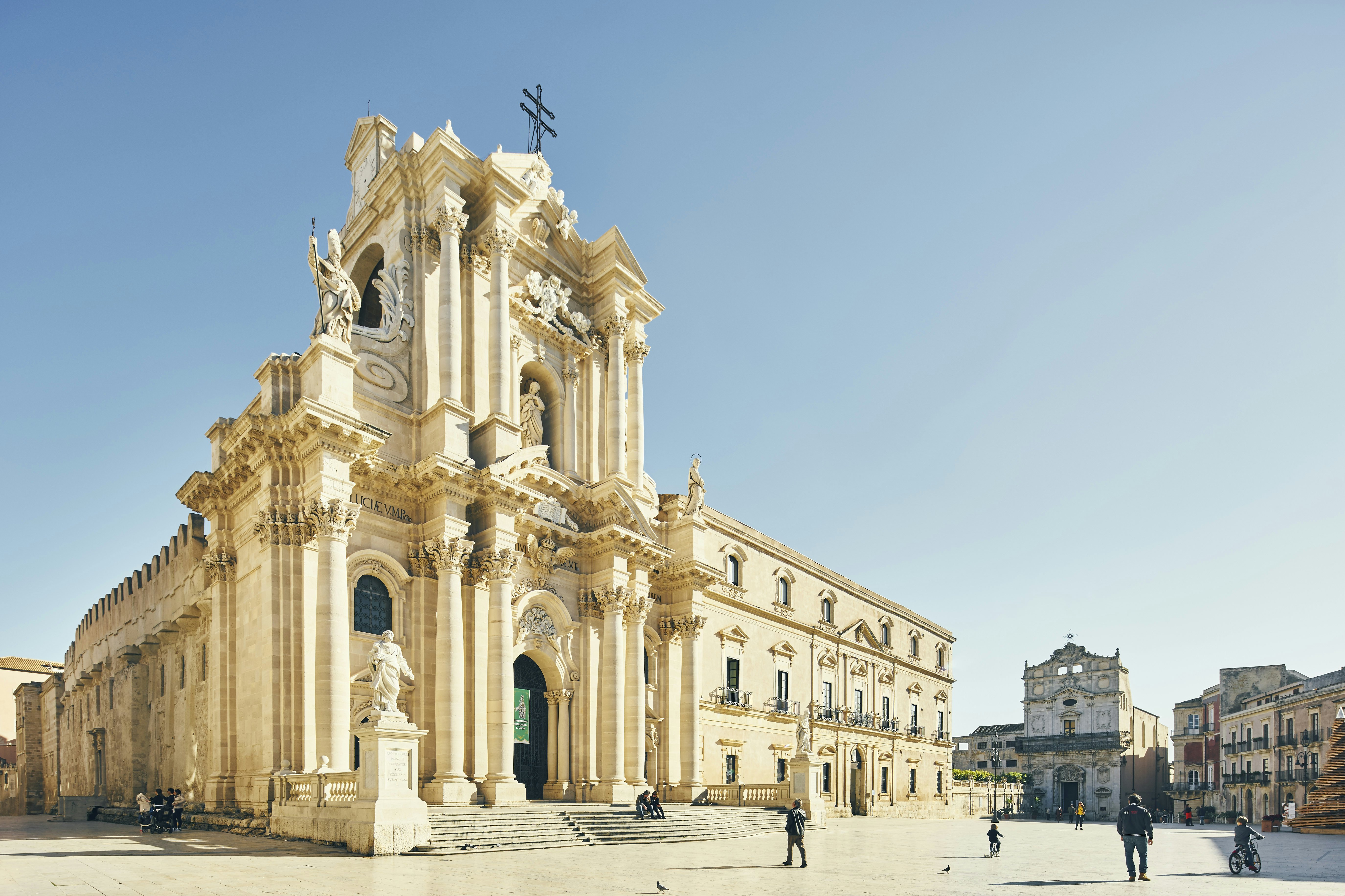 A large white church on the edge of a city square lined with historic buildings.
