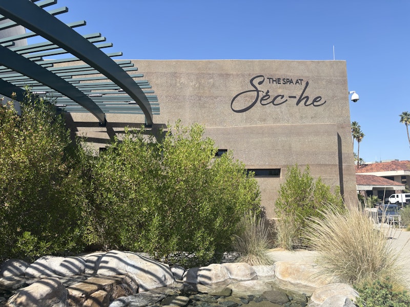 The entrance to a stone building with "The Spa at Séc-he" on its facade