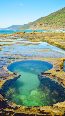 Natural pool in the shape of an eight, filled with turquoise water and surrounded by marsh.