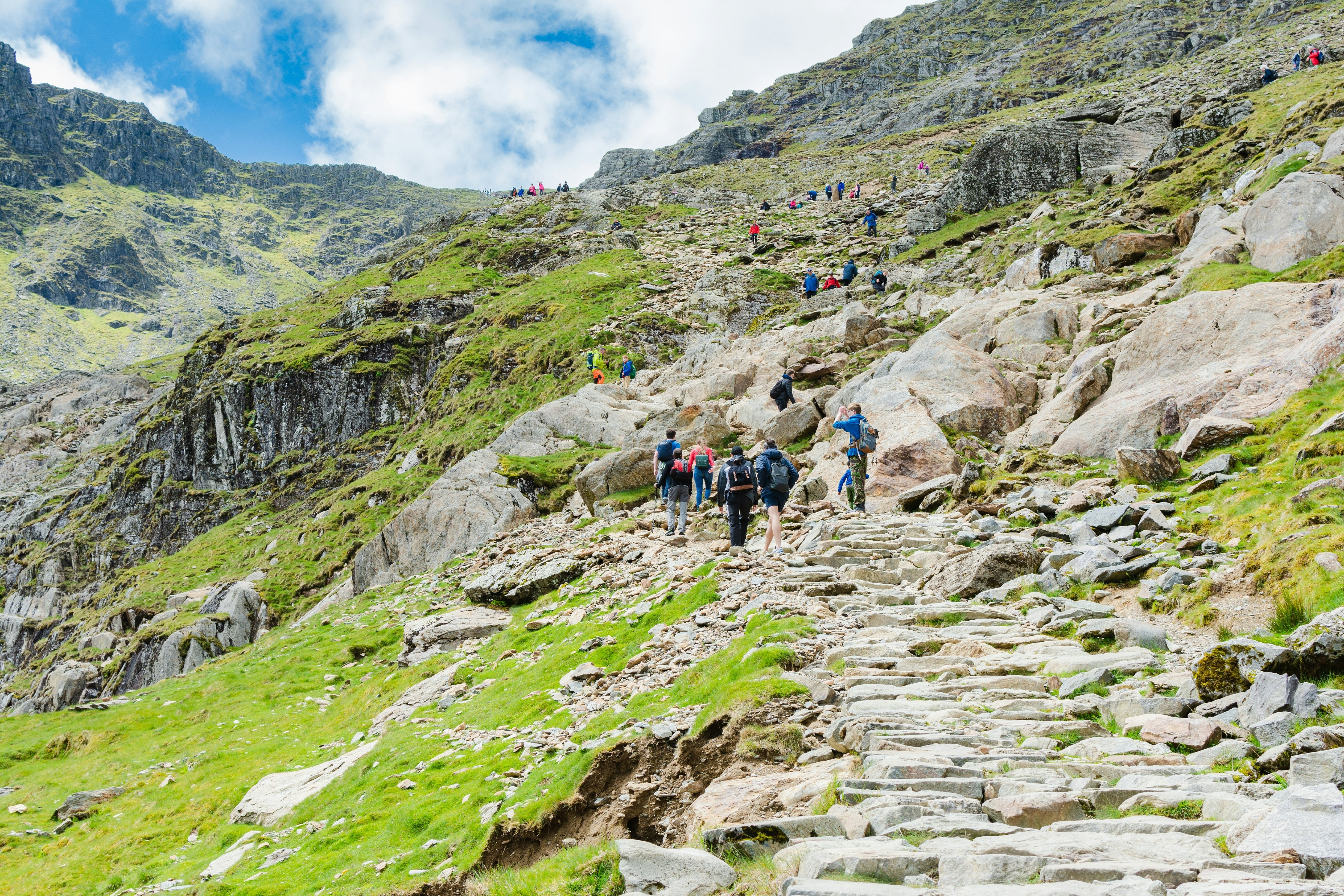 Snowdonia, Wales: People Climbing up the mount Snowdon in North Wales, view of the stone path, mountains, green grass