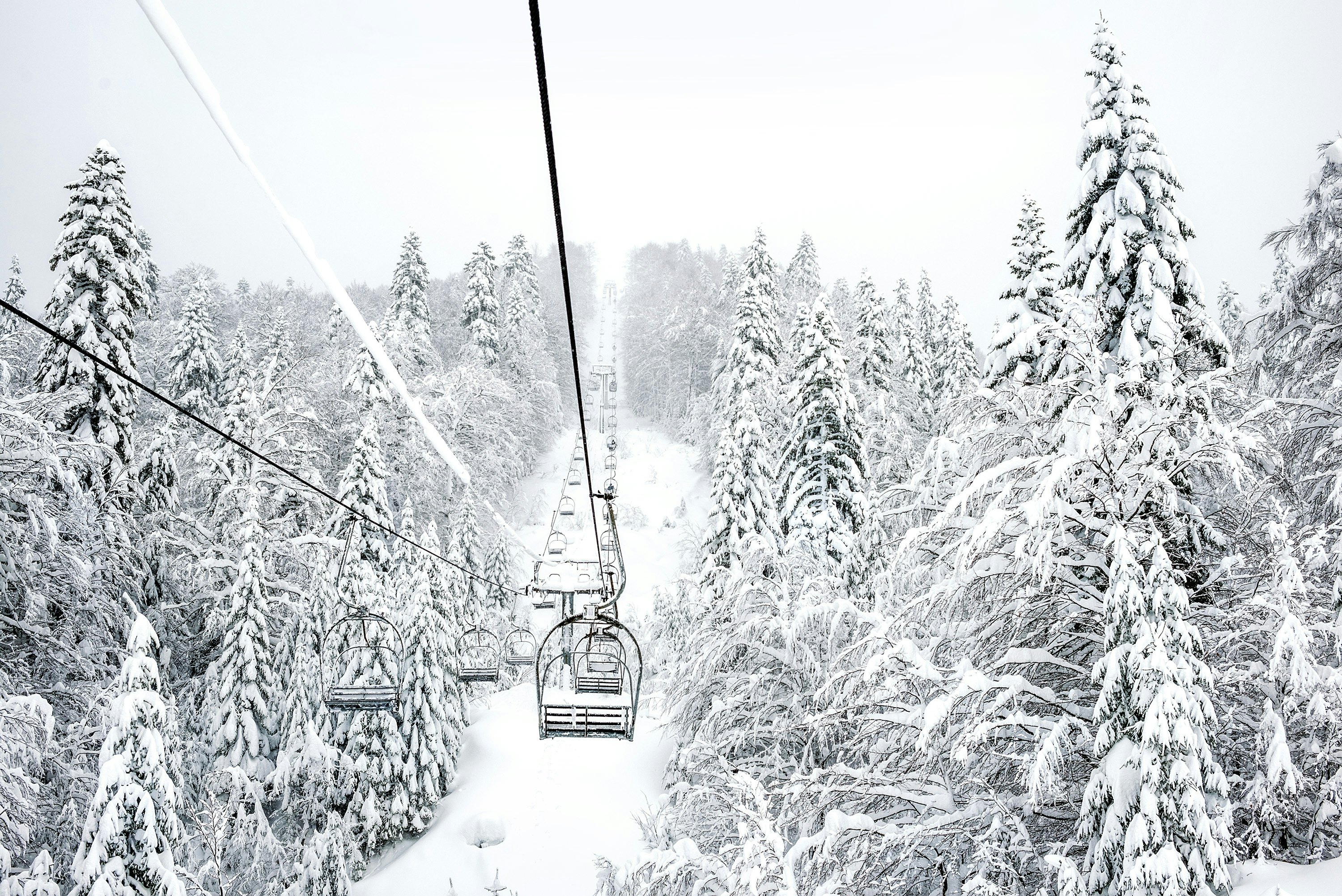 An empty ski lift through very snowy trees in Montenegro.