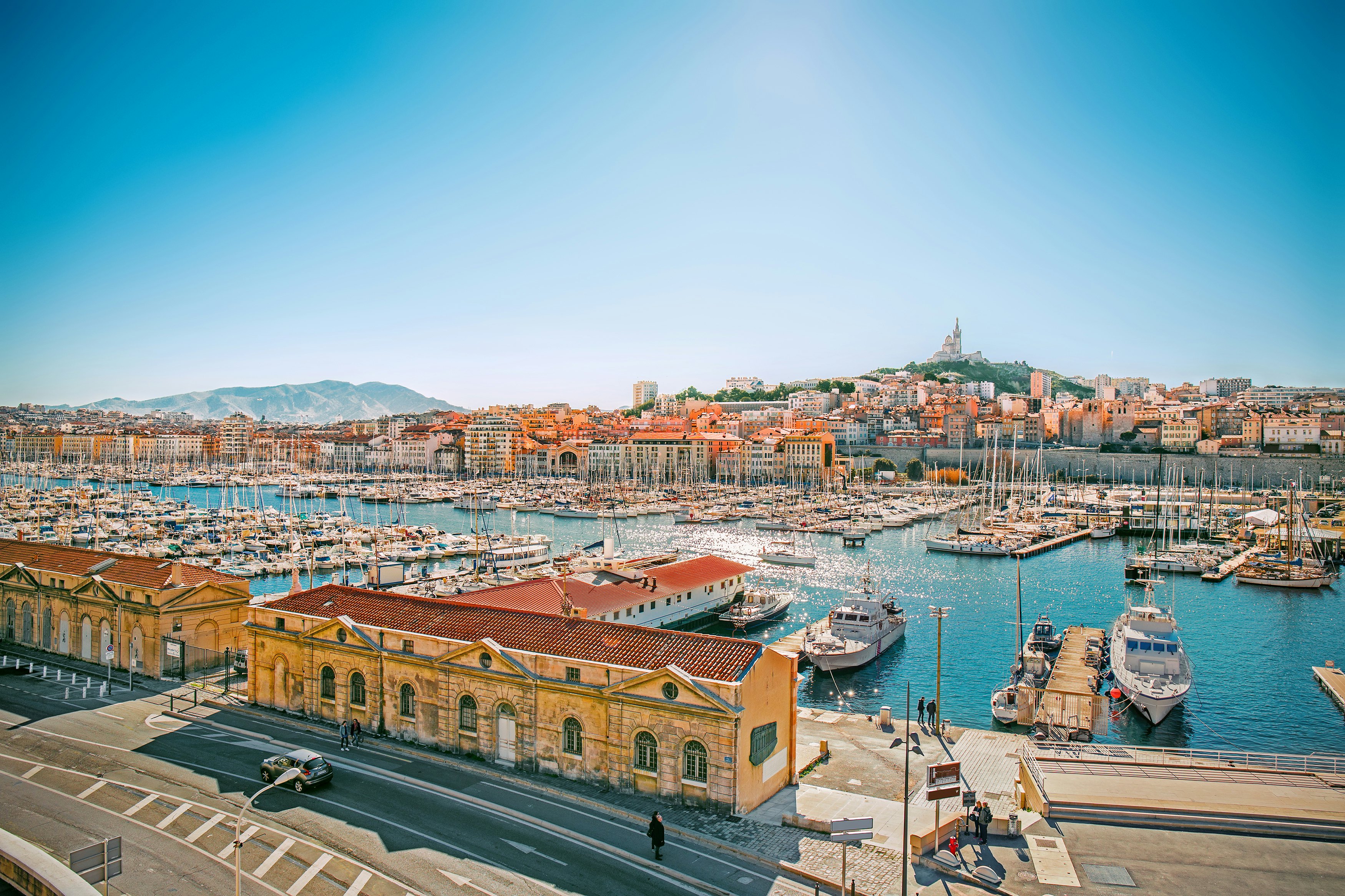 Boats in a marina of a port city in France with blue sky and distant church
