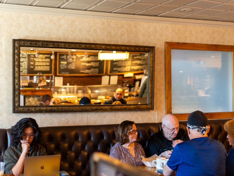 customers sit at tables on a leather bench at Thinking Cup