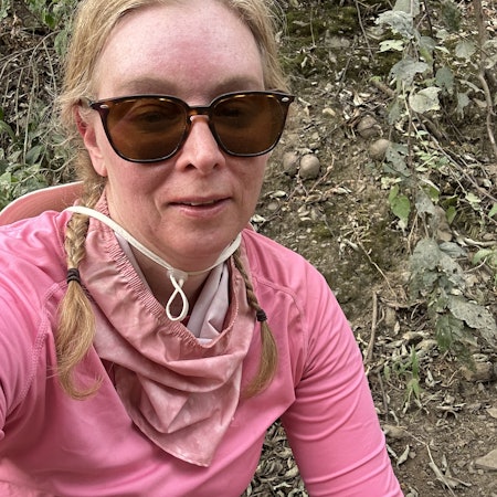 Woman in pink top and sunglasses appears tired