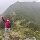 Lonely Planet Editor Melissa Yeager standing in rain with view of Choquequirao in Peru