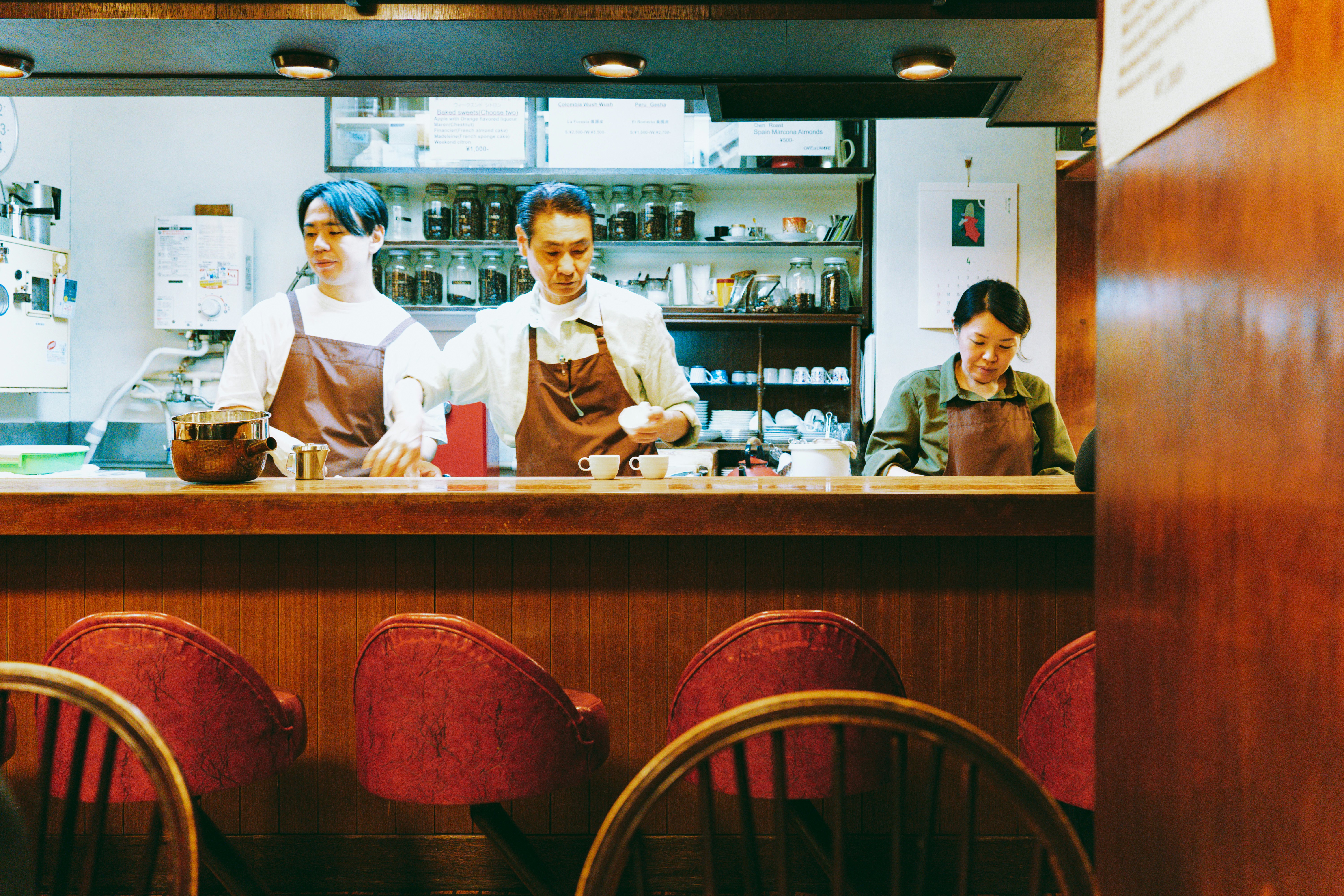 Three workers behind the counter at Cafe de L'ambre in Tokyo