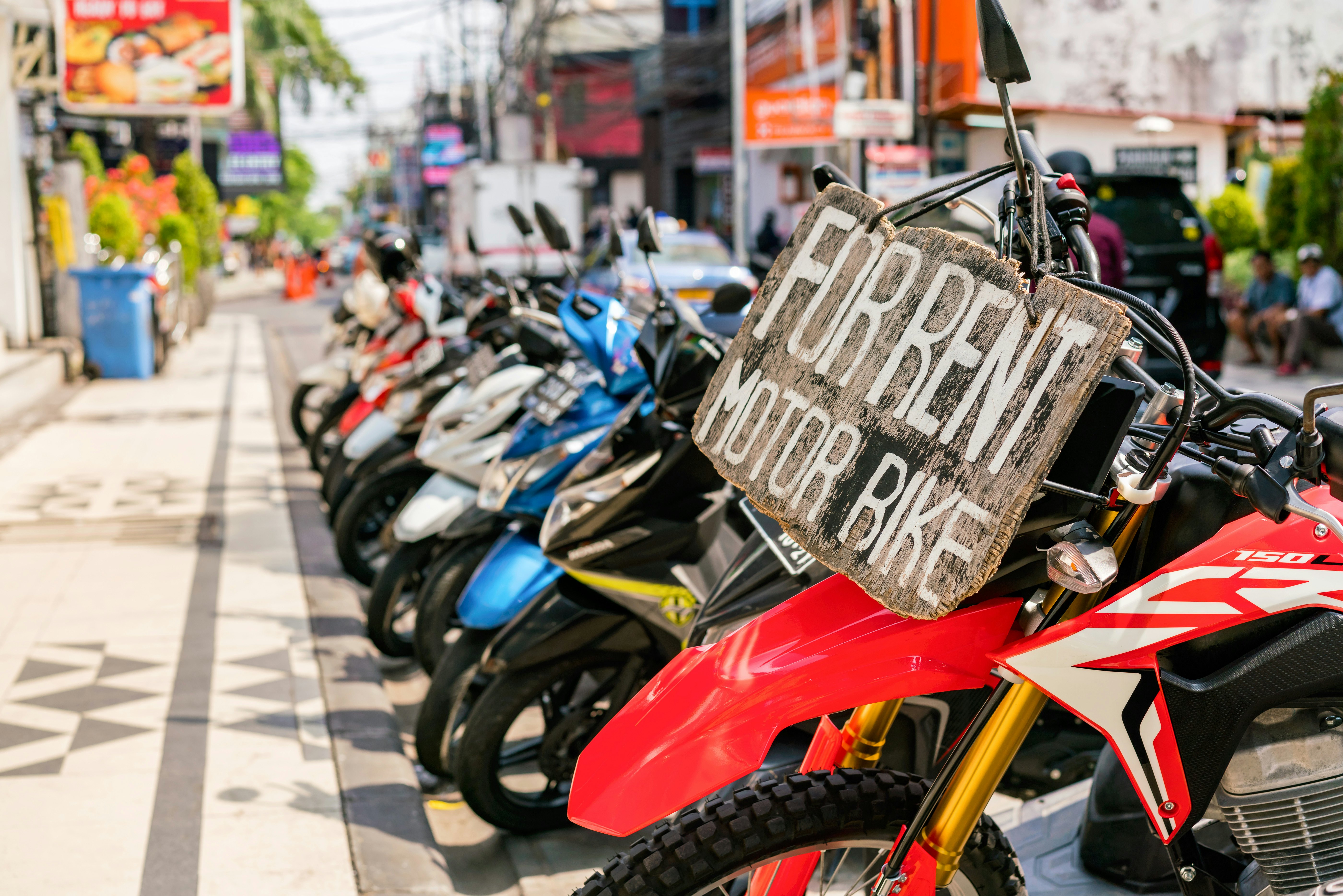 Motorcycles and scooters for rent on Legian Street in Kuta, Bali, Indonesia.
