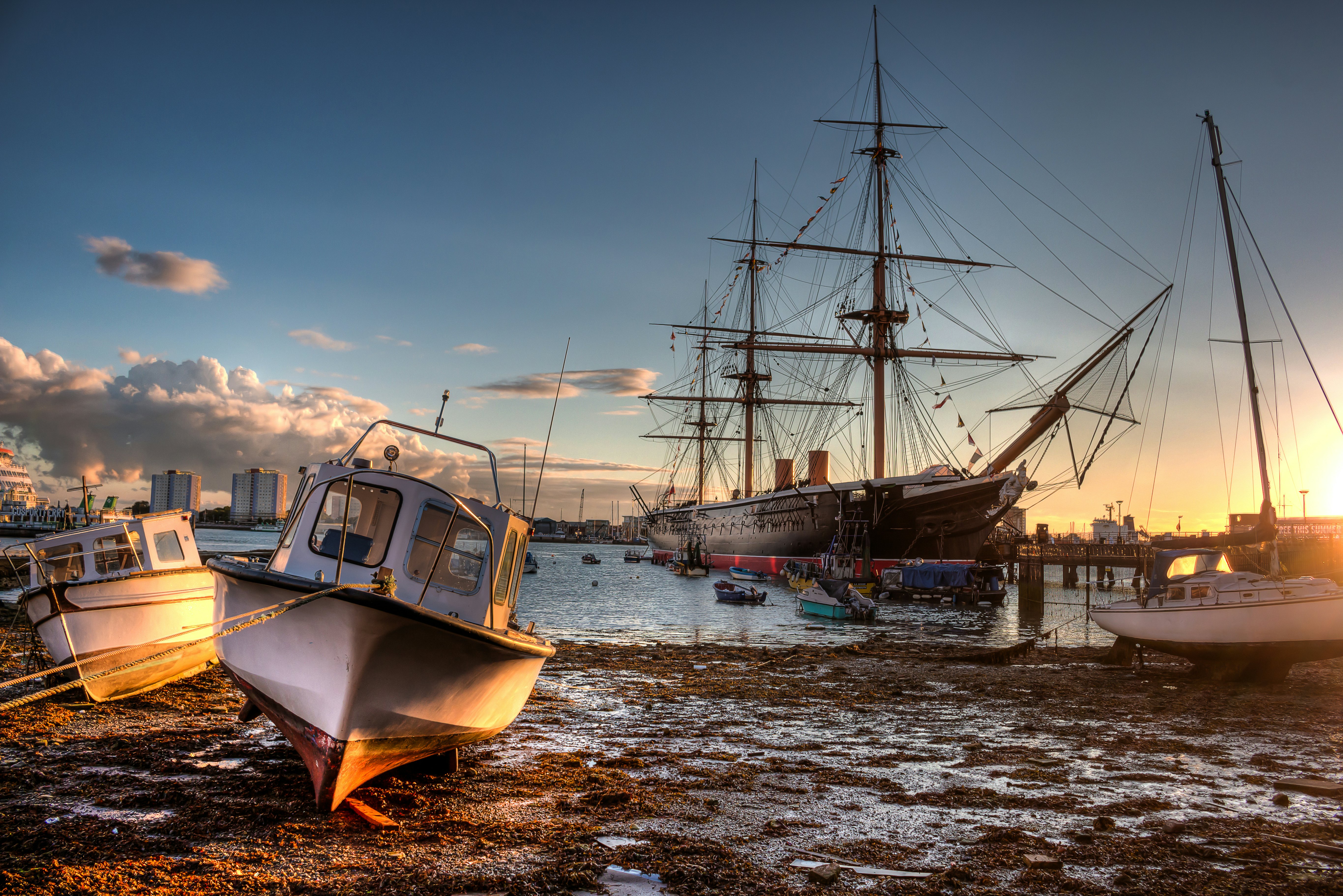 Portsmouth harbor at sunset with small boats and HMS Warrior in the background.