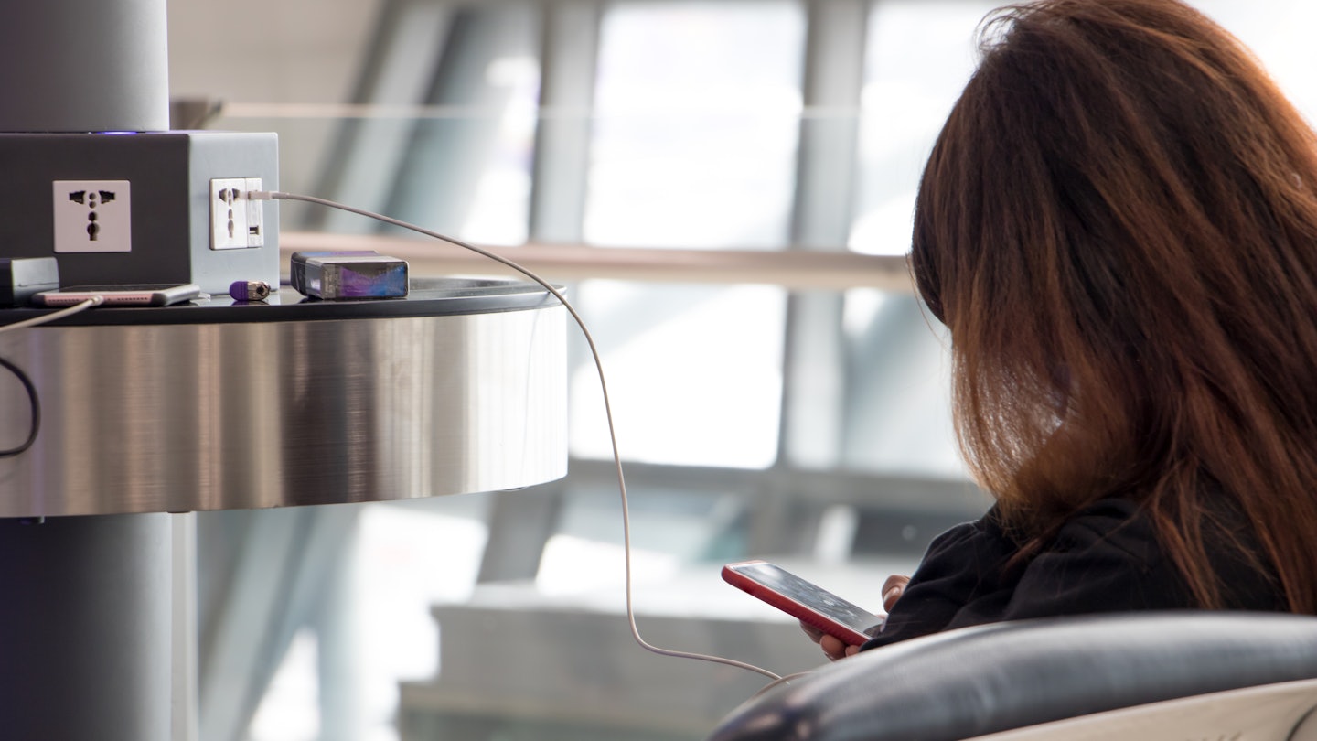A young woman sitting at a charging station and looking at her smartphone. Recharging mobile phones from free charge station at the airport., License Type: media, Download Time: 2025-06-19T20:26:35.000Z, User: adouglaslott59, Editorial: false, purchase_order: 65050 - Digital Destinations and Articles, job: Online editorial, client: Phone hackers at the airport, other: Ann Douglas Lott