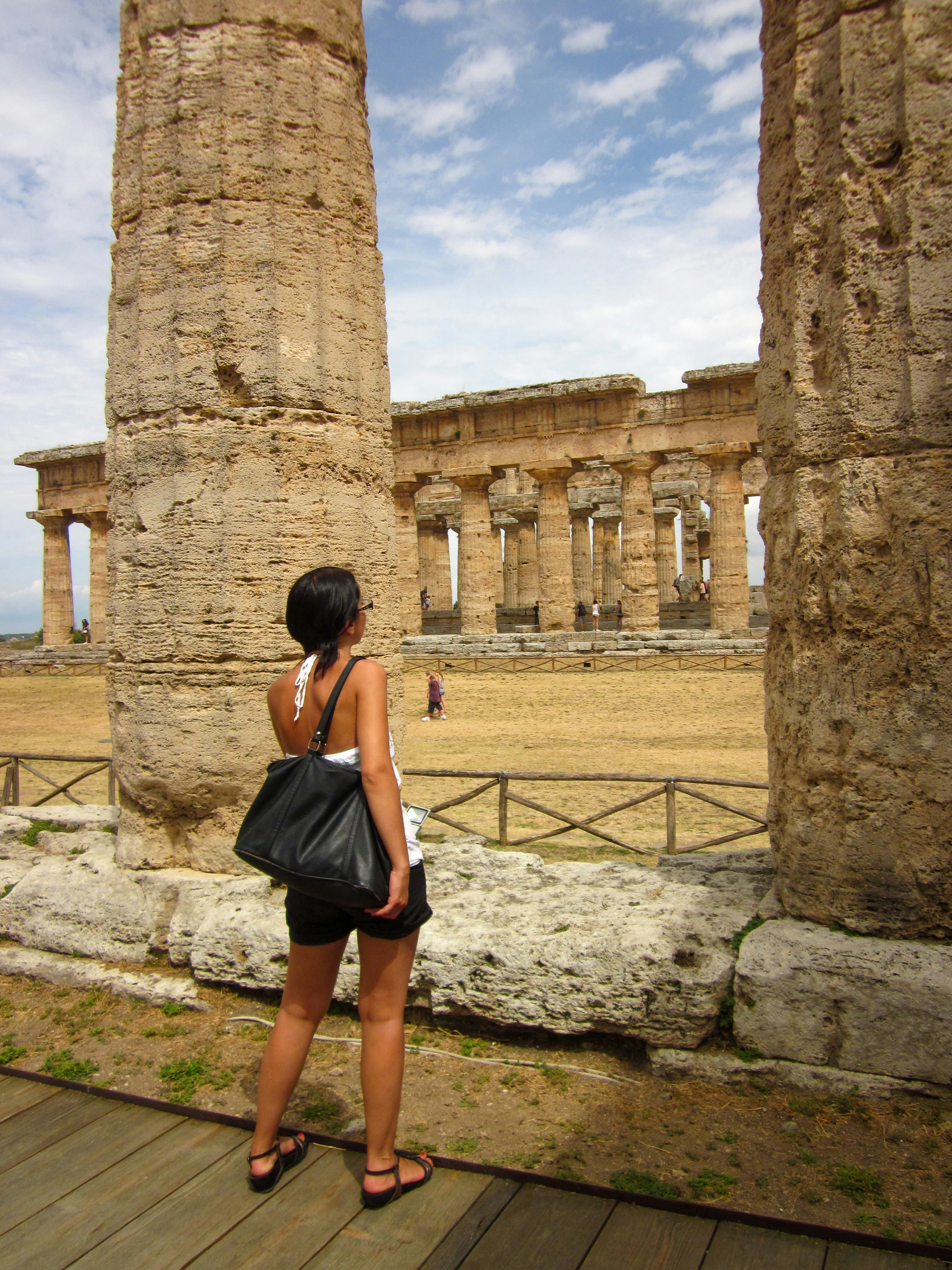 Woman tourist in summer clothes looking at ancient ruins in Italy