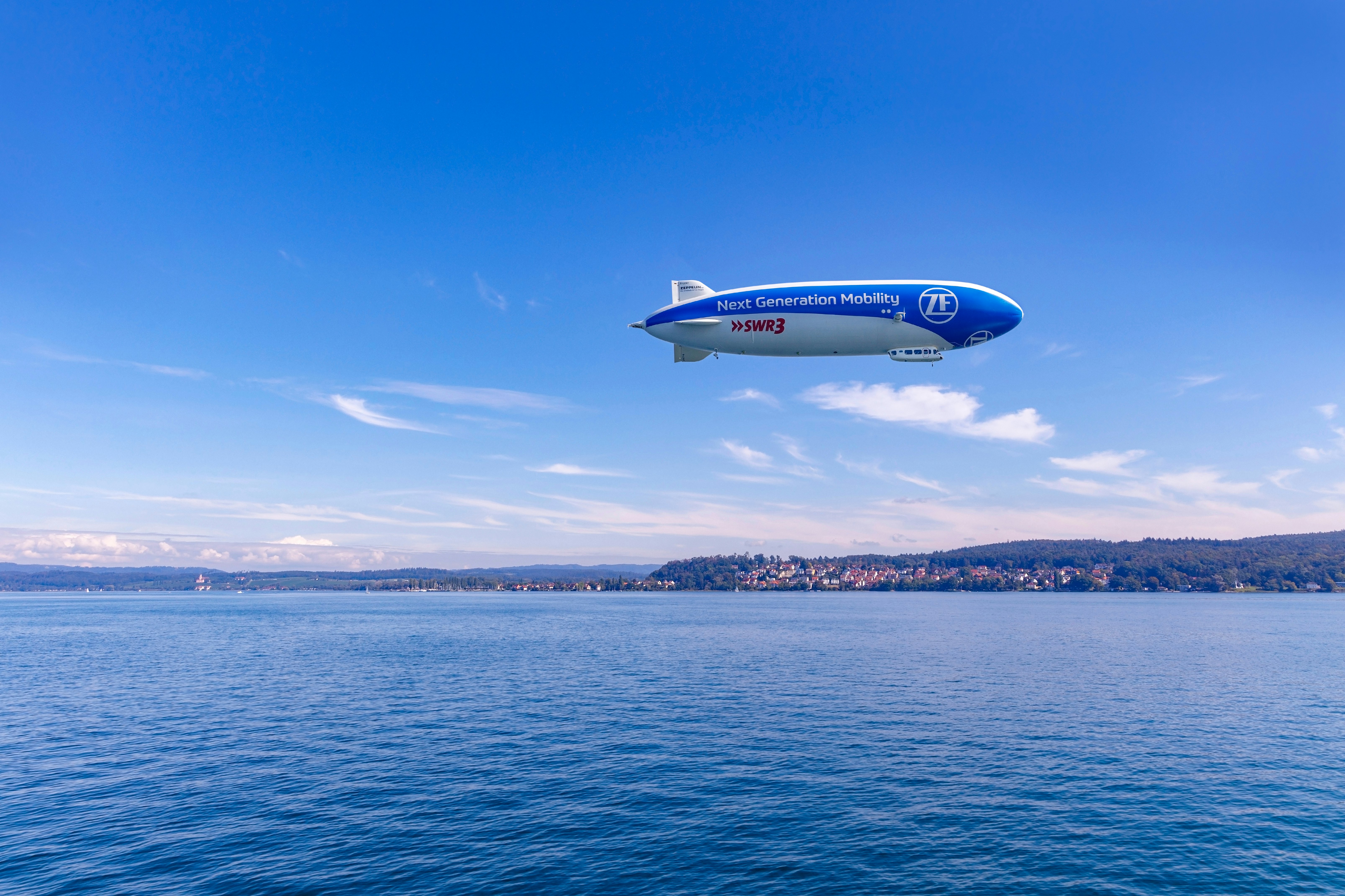 A blimp is pictured low in the sky over a lake.