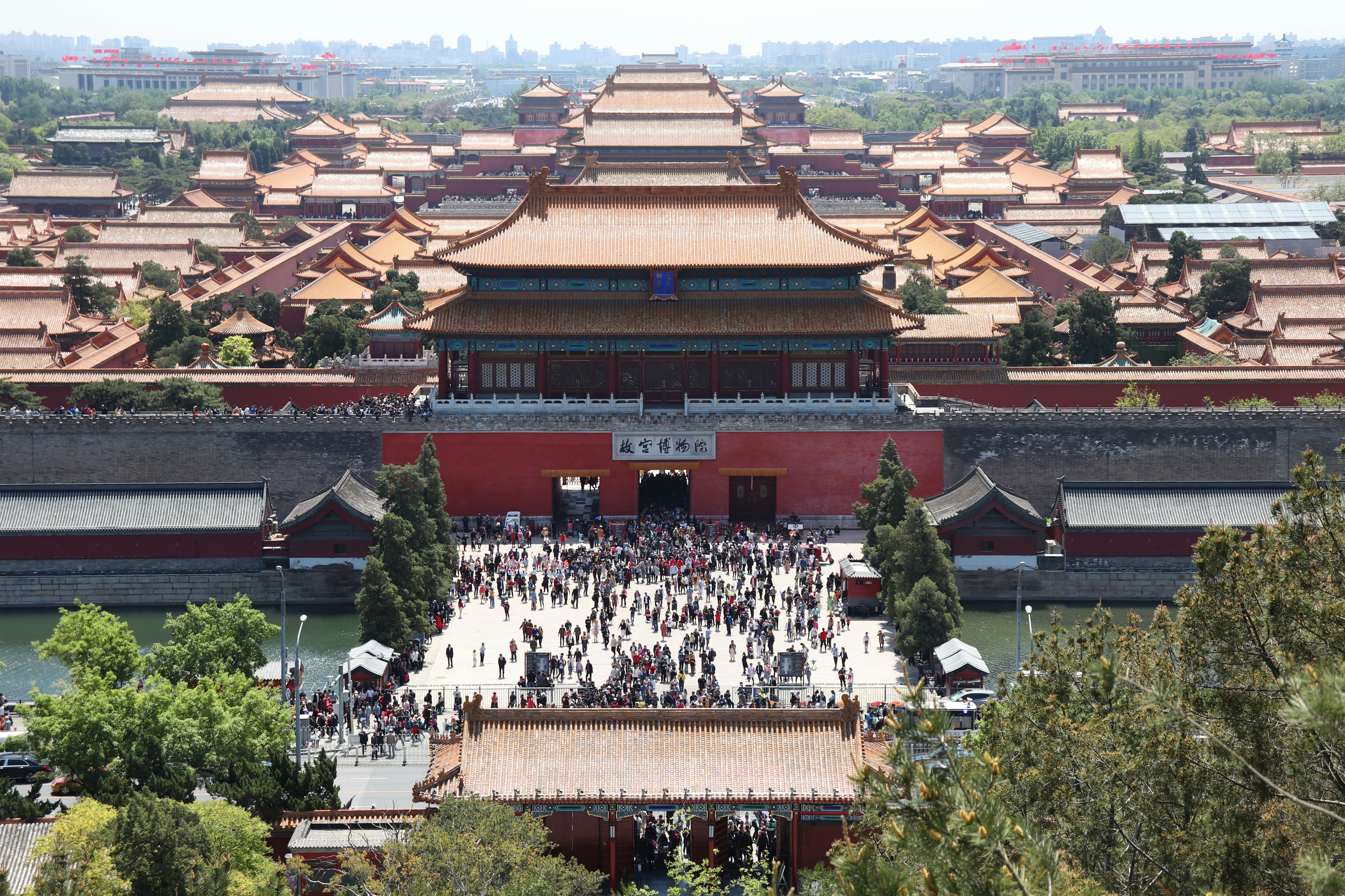 People in a busy square outside a historic walled city.