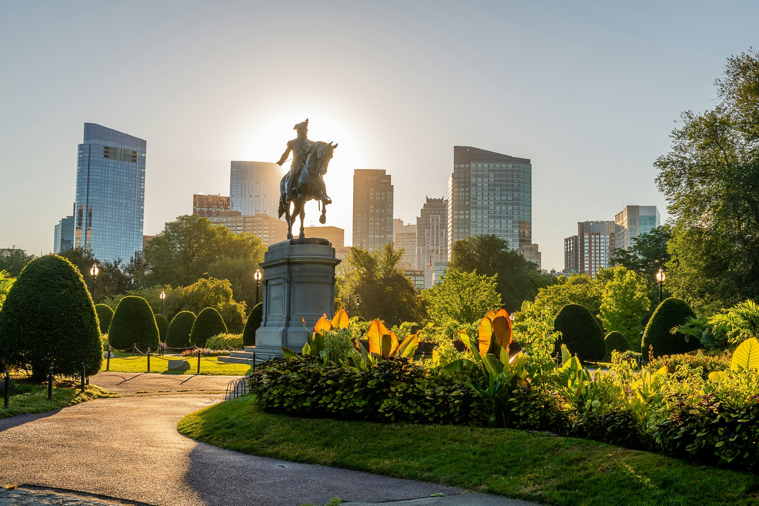 A park in downtown Boston with buildings in the background and a statue of George Washington on a horse