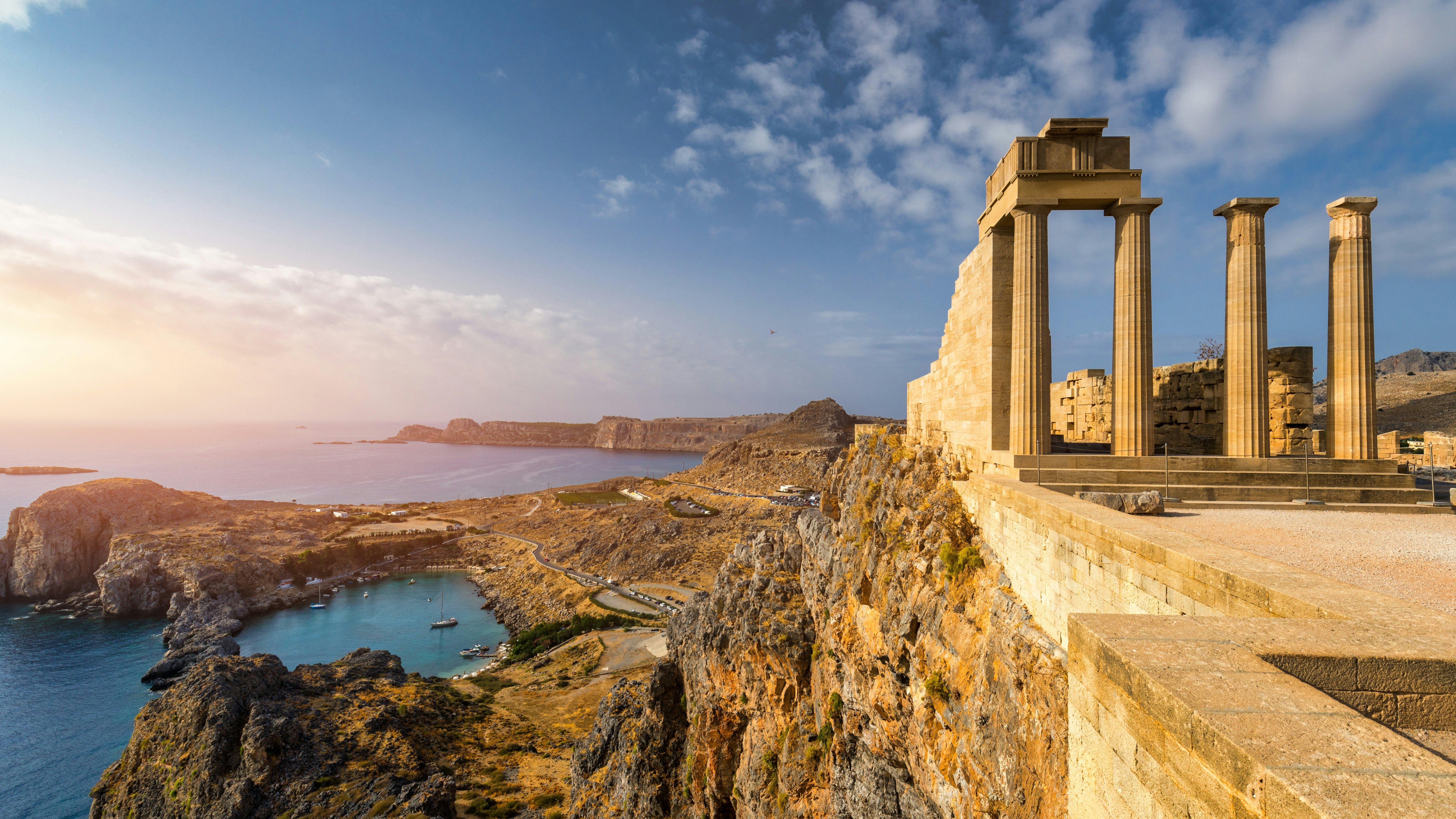 The ruins of an ancient Greek temple on a rocky cliff.