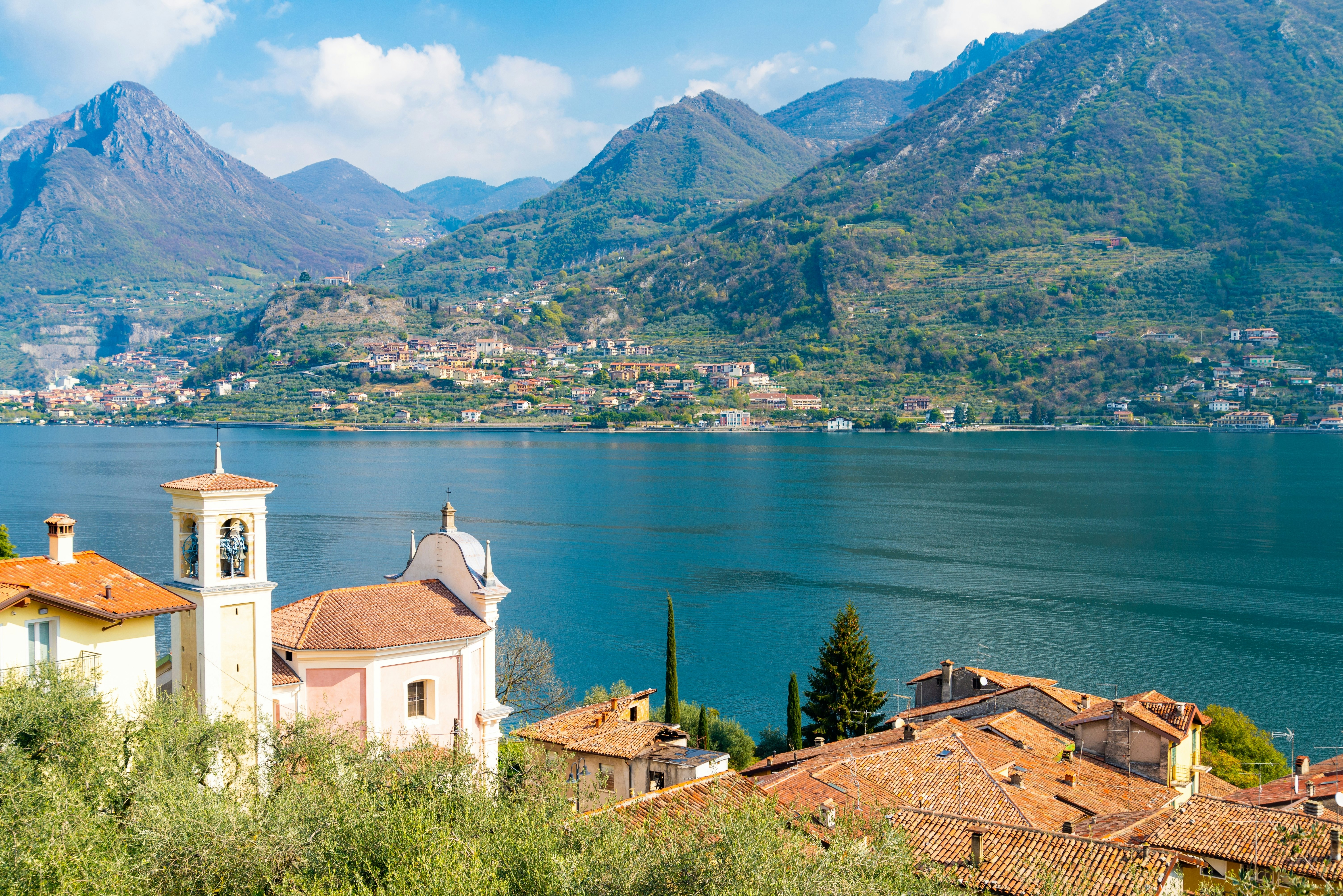 Ancient village in the island named 'Monte Isola' (Mount Island), Lake Iseo, Italy. Aerial view from an hiking trail in the countryside. Italian alps on the background.