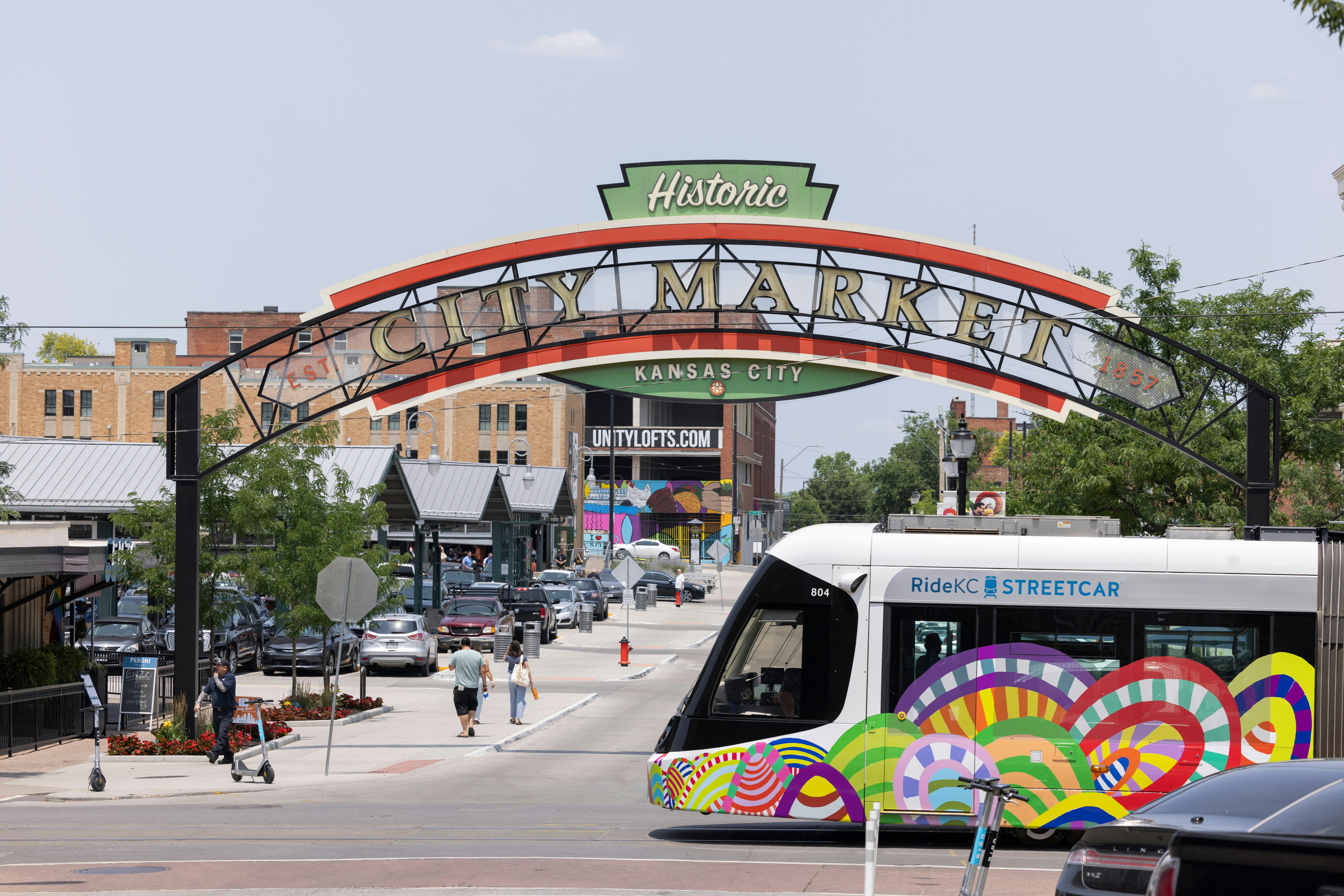 an arched sign stretches across a street with a bus driving past.