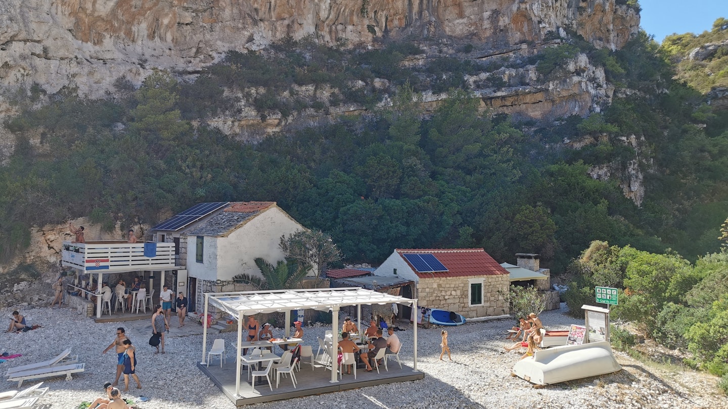 Vis, Croatia - August, 15, 2021: Stiniva a natural hidden beach in the Summer day with people sunbathing behind two large cliffs, with blue sea anbd sky, and lush vegetation in the gorge behind, License Type: media, Download Time: 2025-06-17T19:37:42.000Z, User: Sarahstocking, Editorial: true, purchase_order: 65050 - Digital Destinations and Articles, job: Digital, client: First time guide to Vis, other: Sarah Stocking