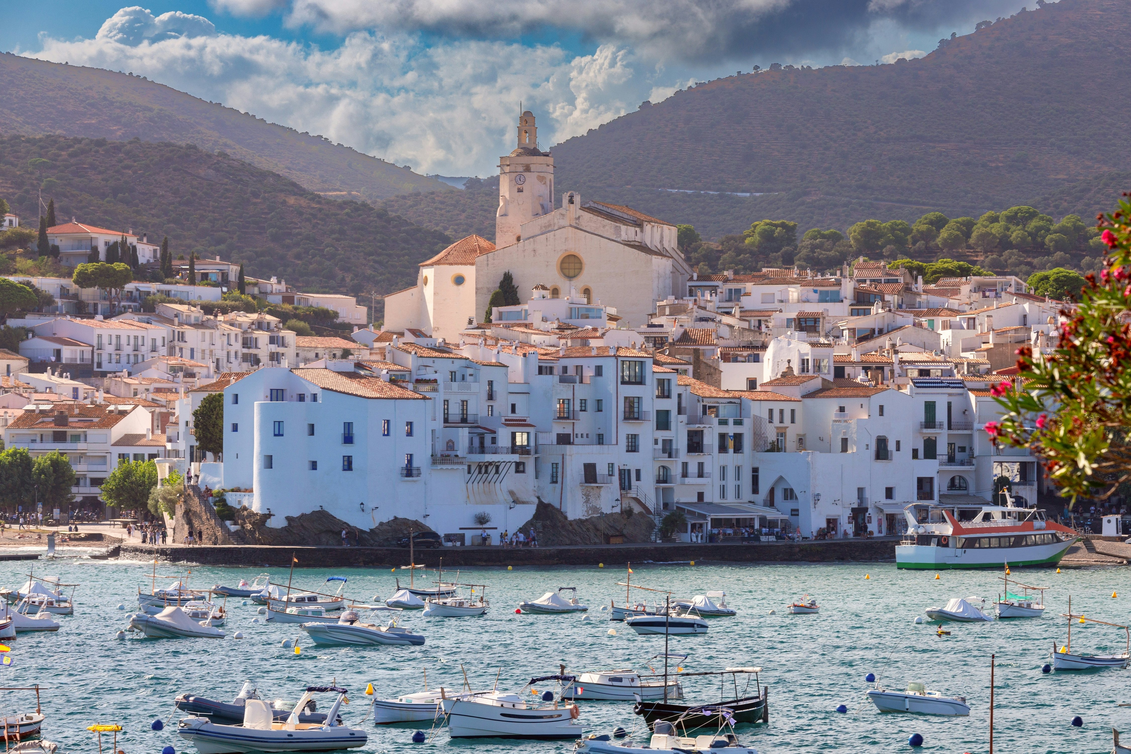 A waterfront dotted with boats and framed with whitewashed buildings and a church