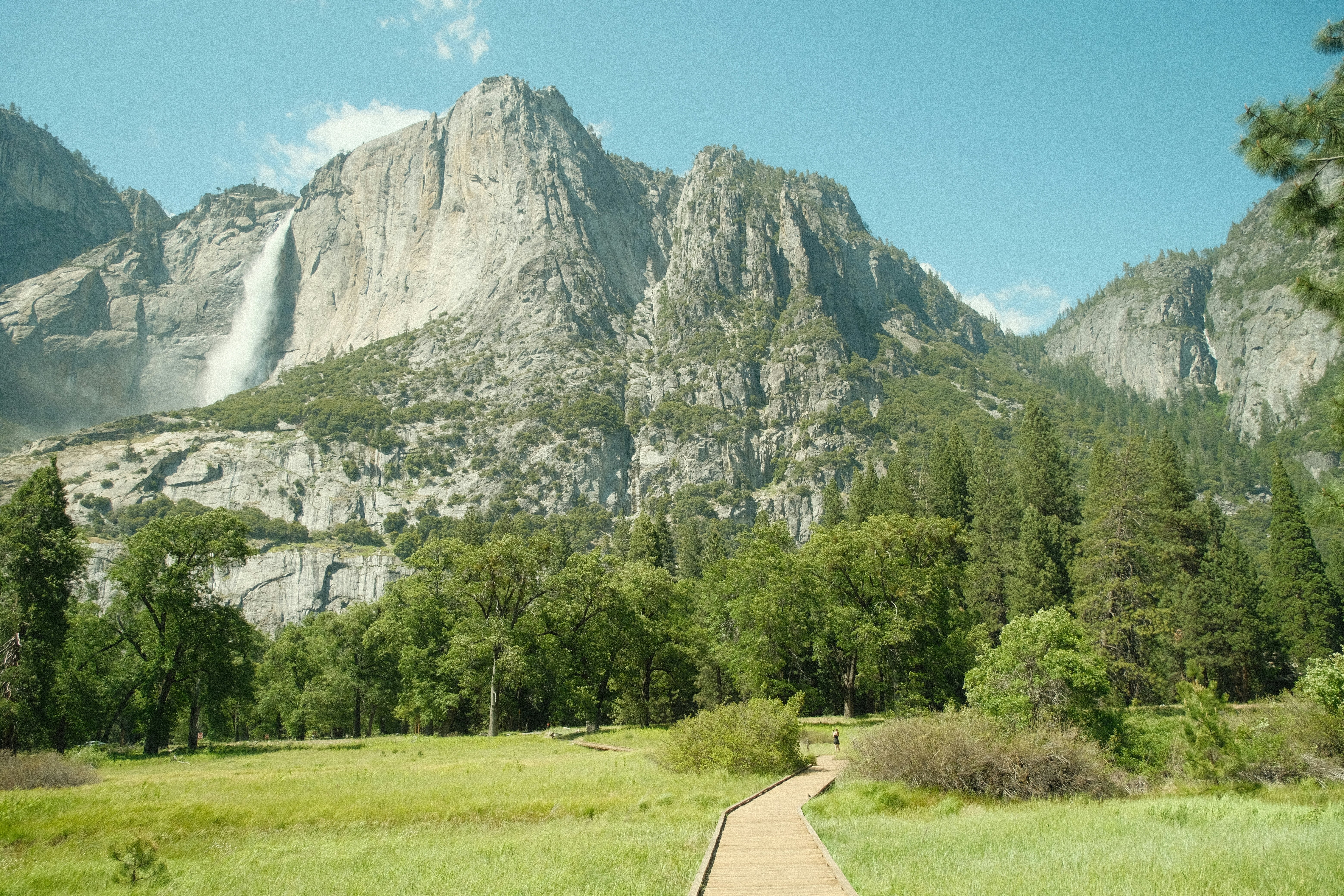 Yosemite National Park in California’s Sierra Nevada mountains green foliage on sunny day with waterfall,