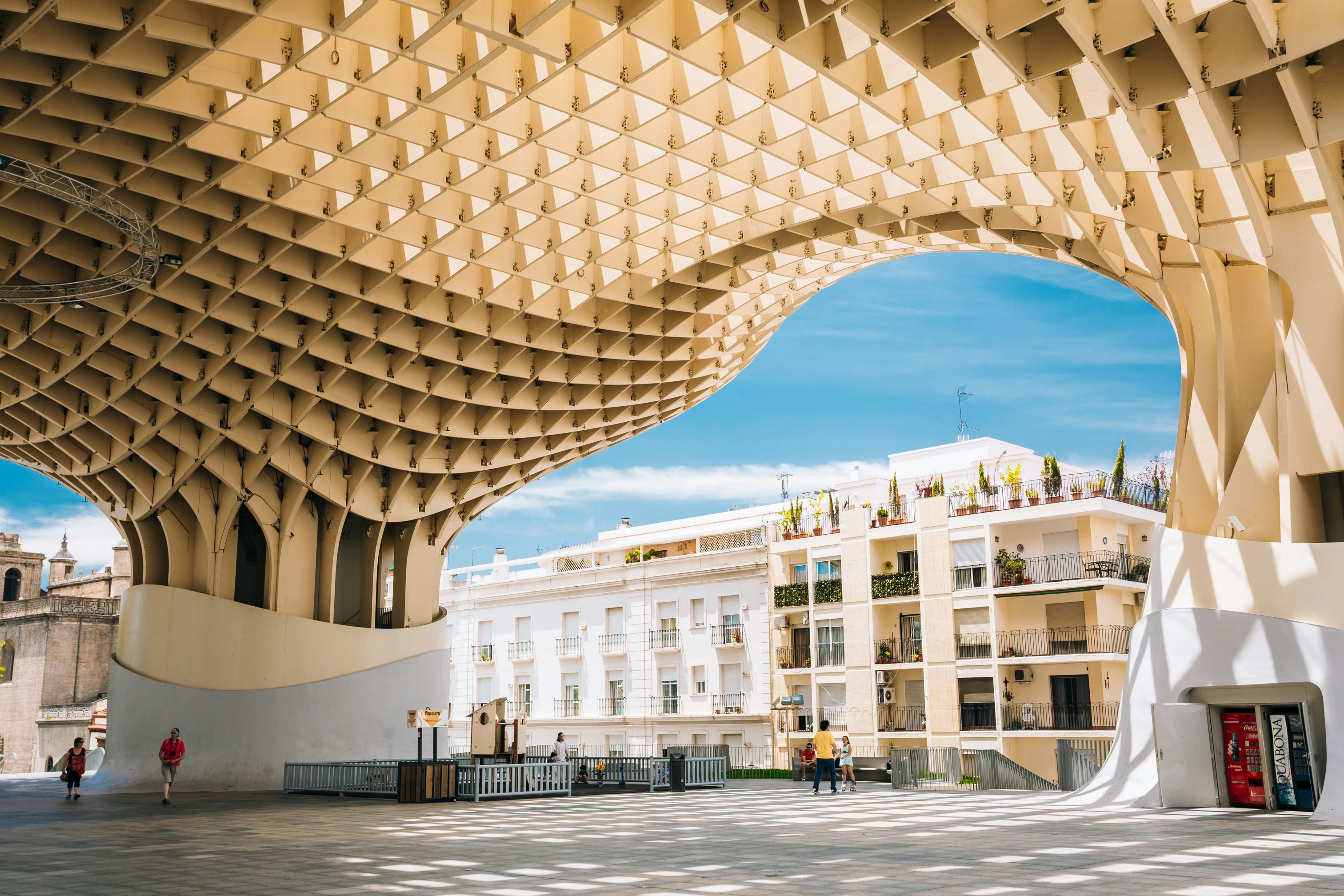 People walk along an elevated walkway with a lattice overhead