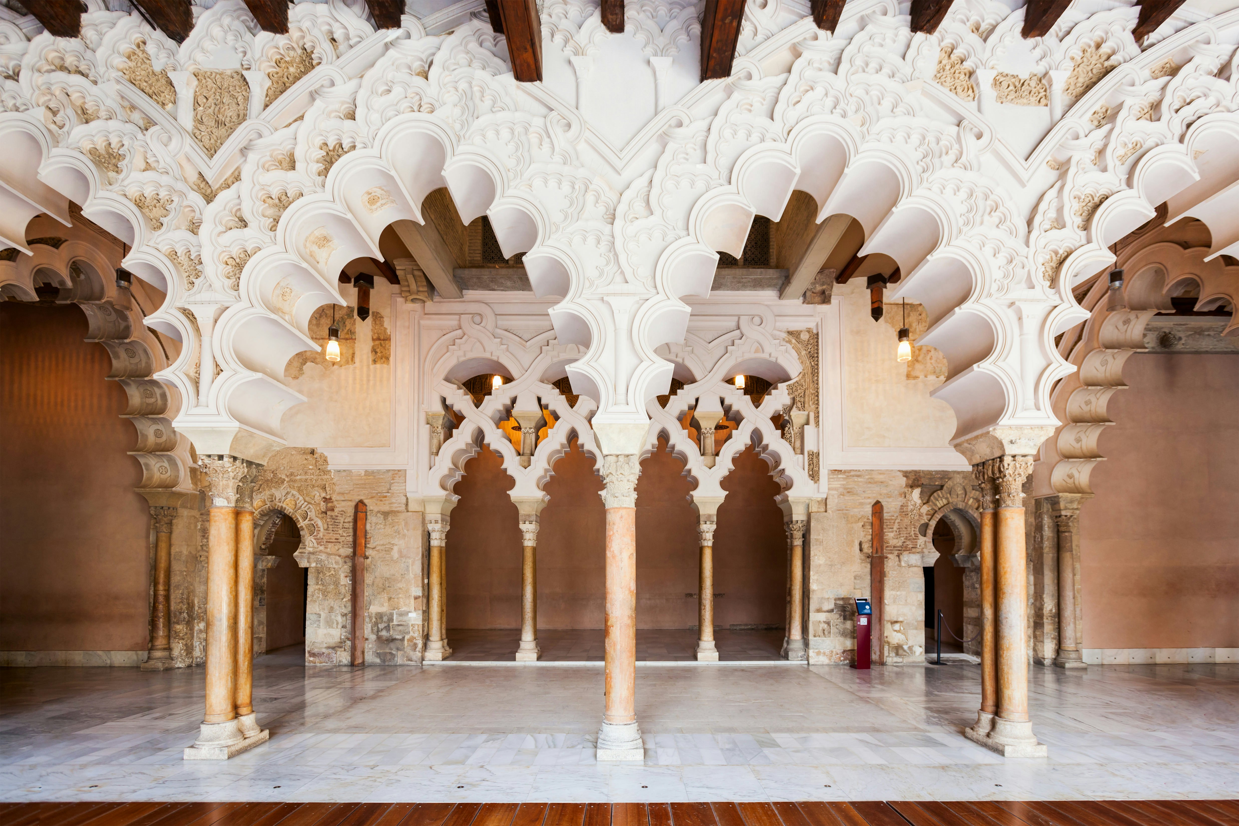 Ornate white archways within a large room in a palace.
